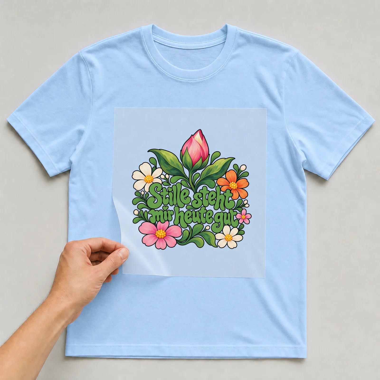 Bügelbild „Stille steht mir heute gut“ auf hellblauem T-Shirt, Folie wird aufgelegt