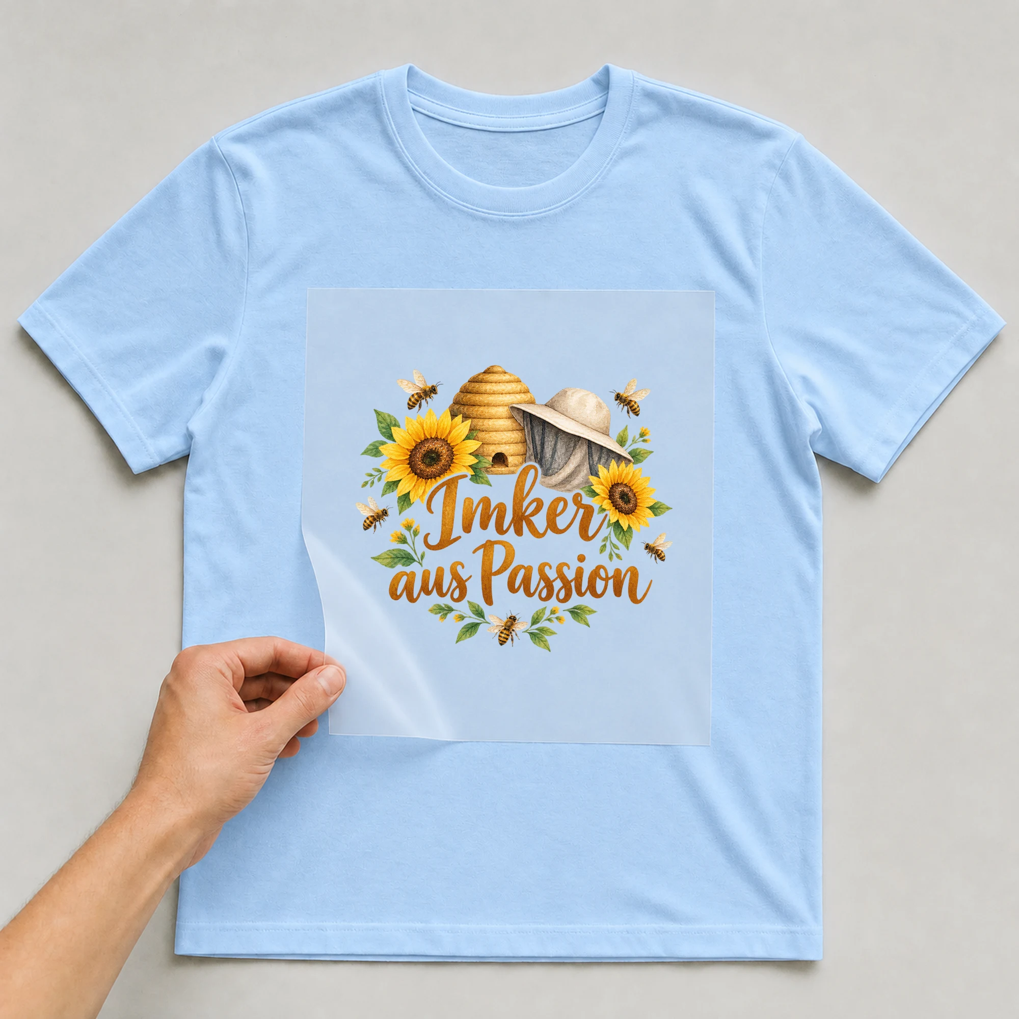 Bügelbild „Imker aus Passion“ auf babyblauem T-Shirt, Folie wird aufgelegt