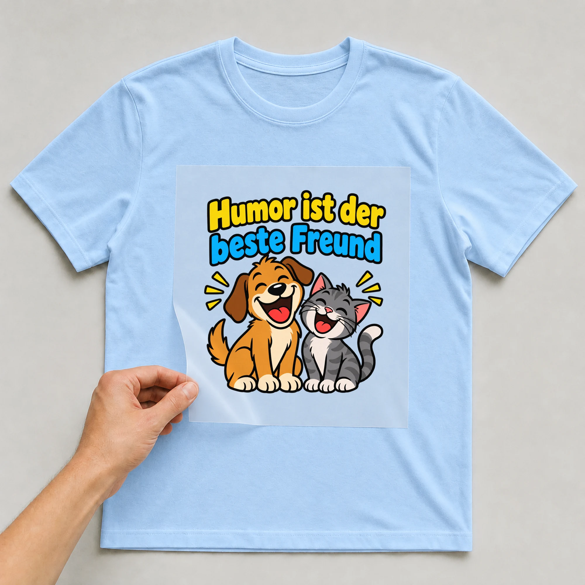 Bügelbild „Humor ist der beste Freund“ auf babyblauem T-Shirt, Folie wird aufgelegt