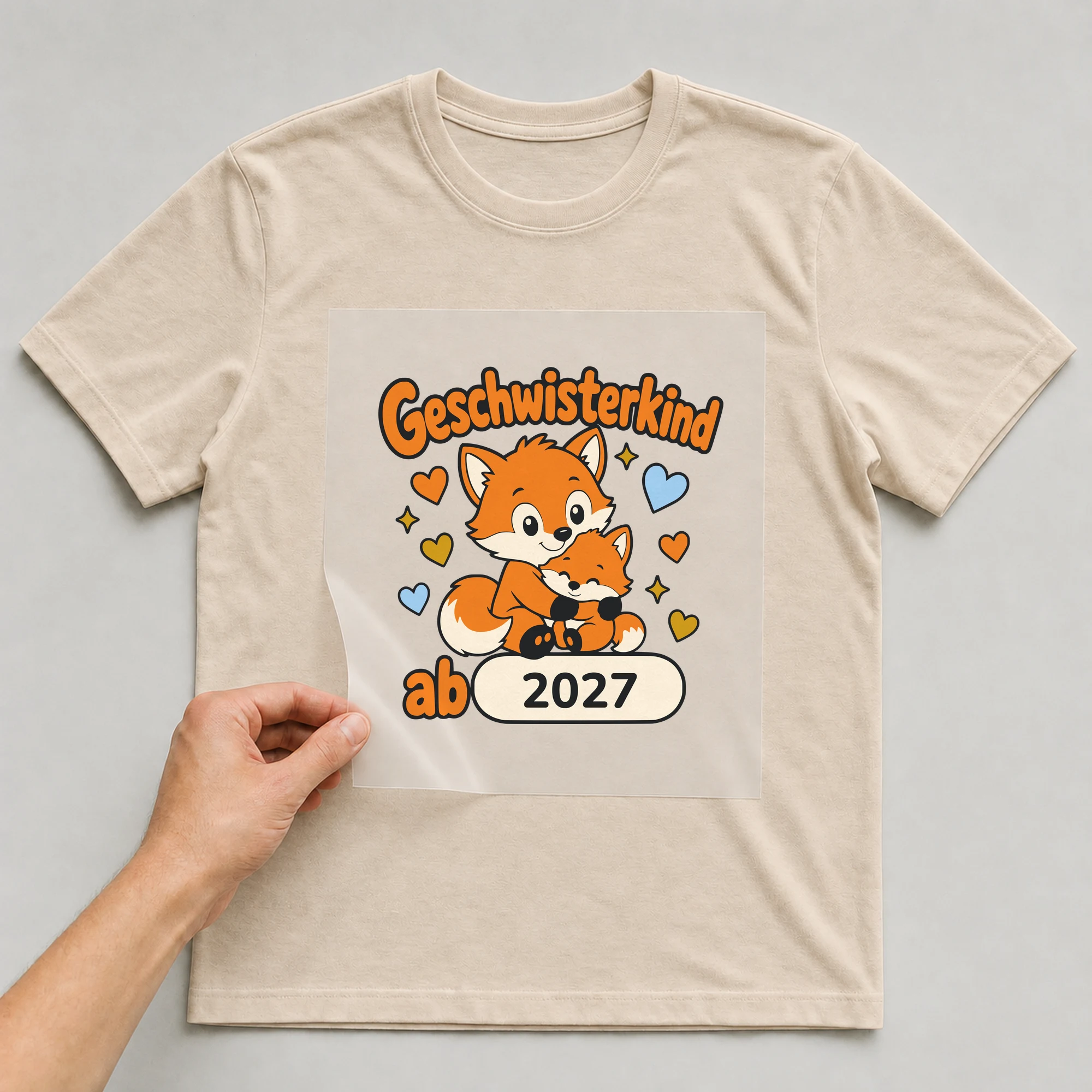 Bügelbild Geschwisterkind mit Jahr auf beigem T-Shirt, Folie wird aufgelegt