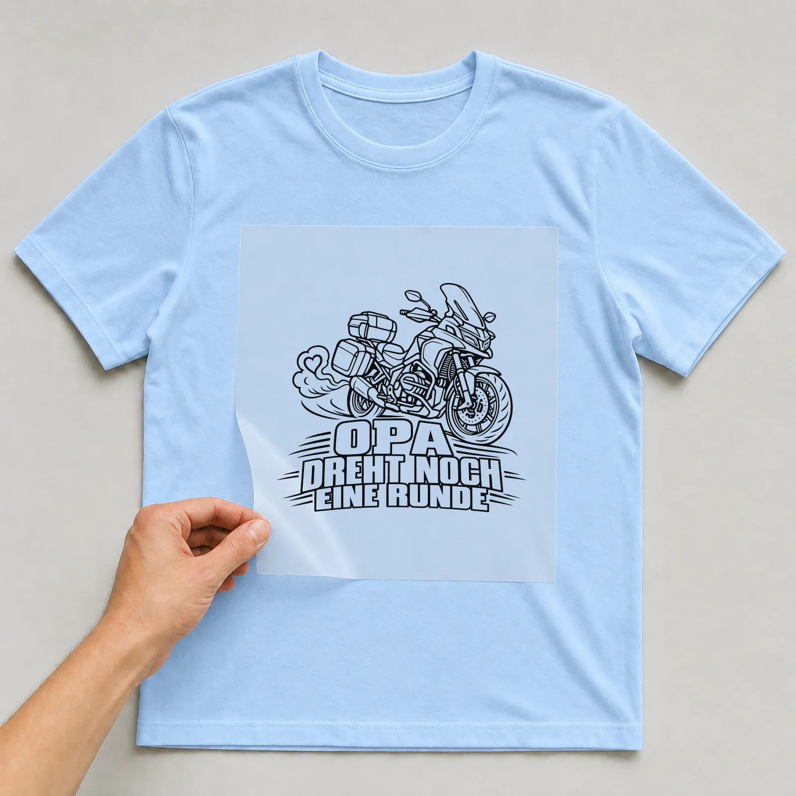 Bügelbild „Opa dreht noch eine Runde“ auf hellblauem T-Shirt, Folie wird aufgelegt