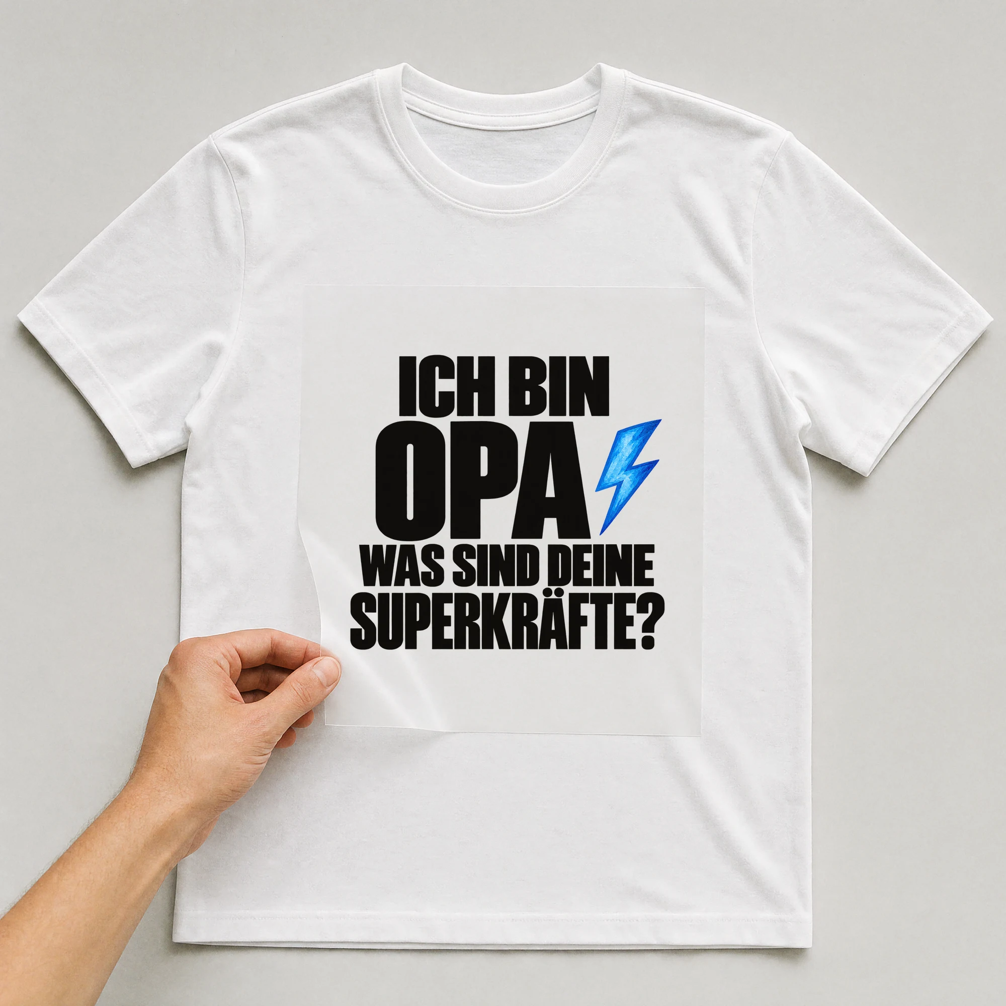 Bügelbild „Ich bin Opa was sind deine Superkräfte?“ auf weißem T-Shirt, Folie wird aufgelegt
