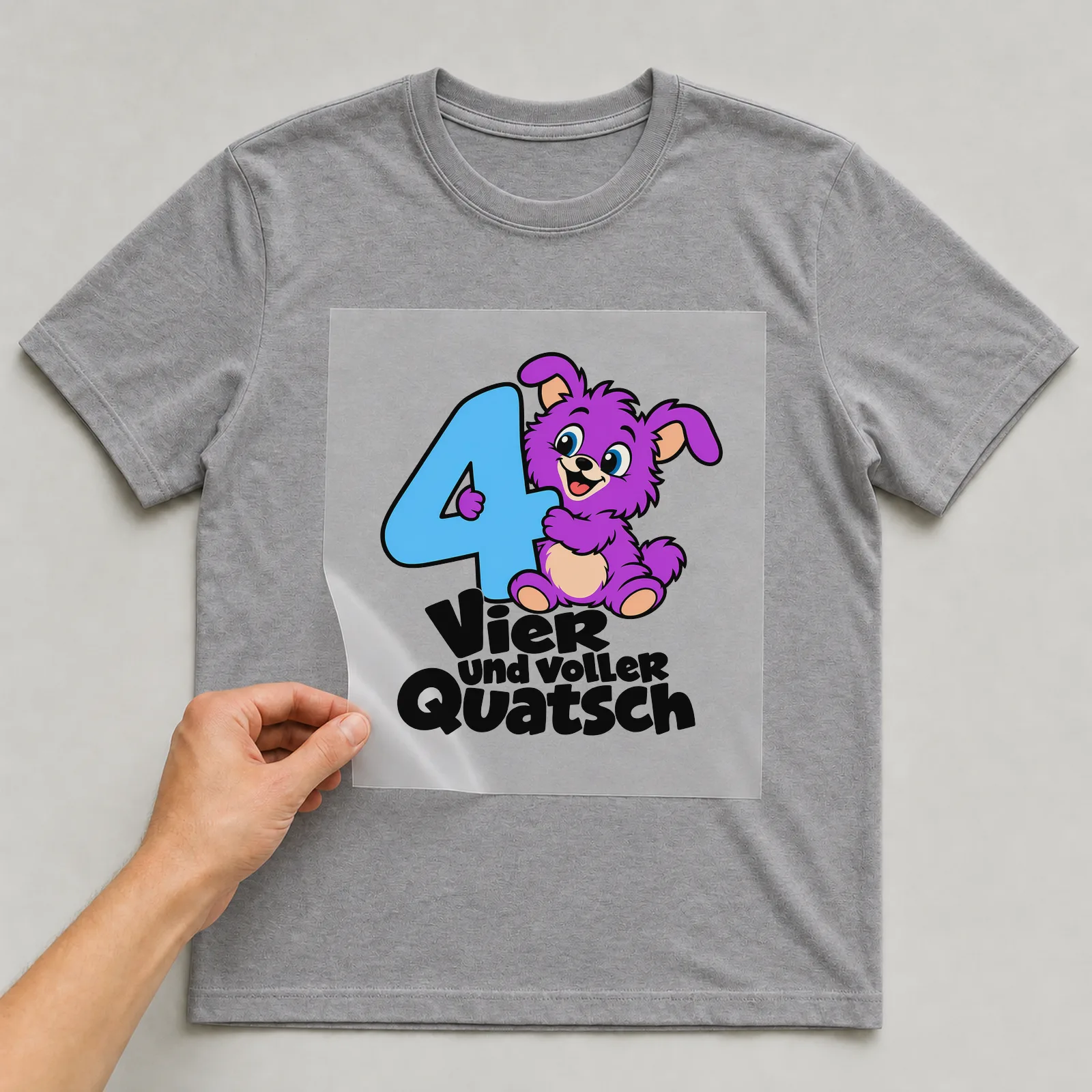 Bügelbild „Vier und voller Quatsch“ auf grauem T-Shirt, Folie wird aufgelegt