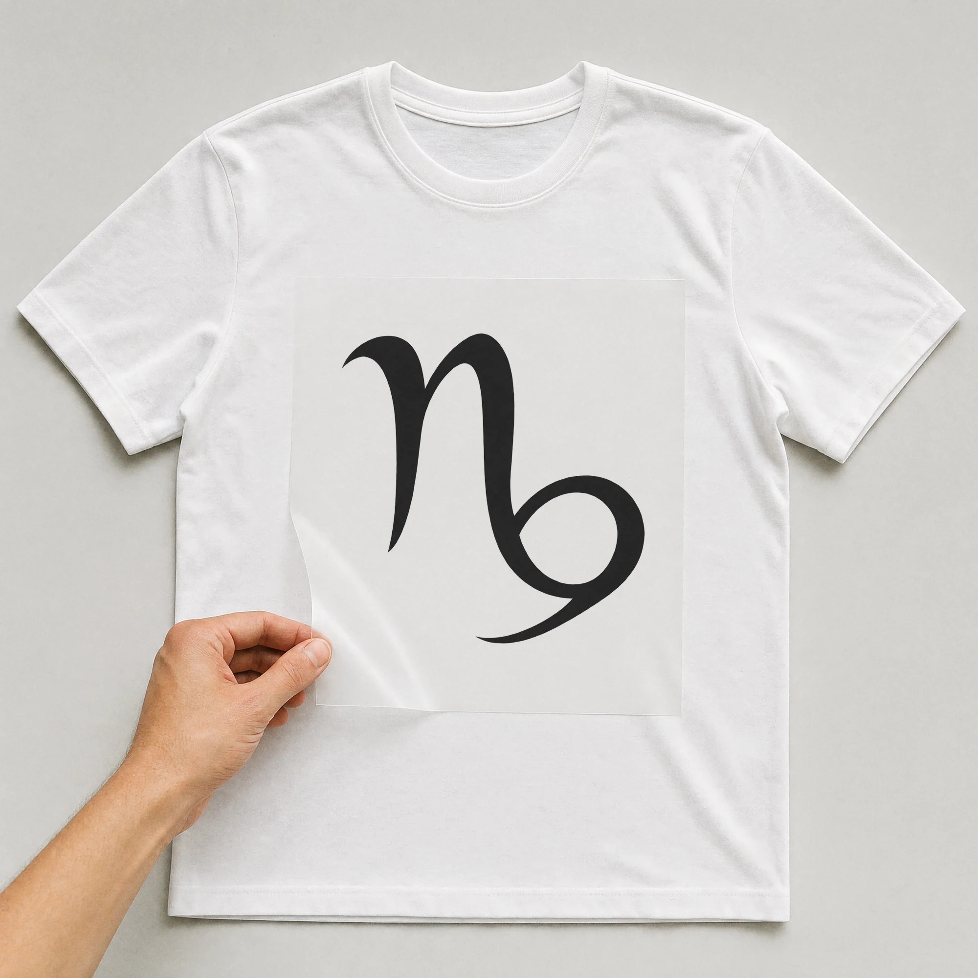 Bügelbild „Steinbock Zeichen Abstrakt“ auf weißem T-Shirt, Folie wird aufgelegt
