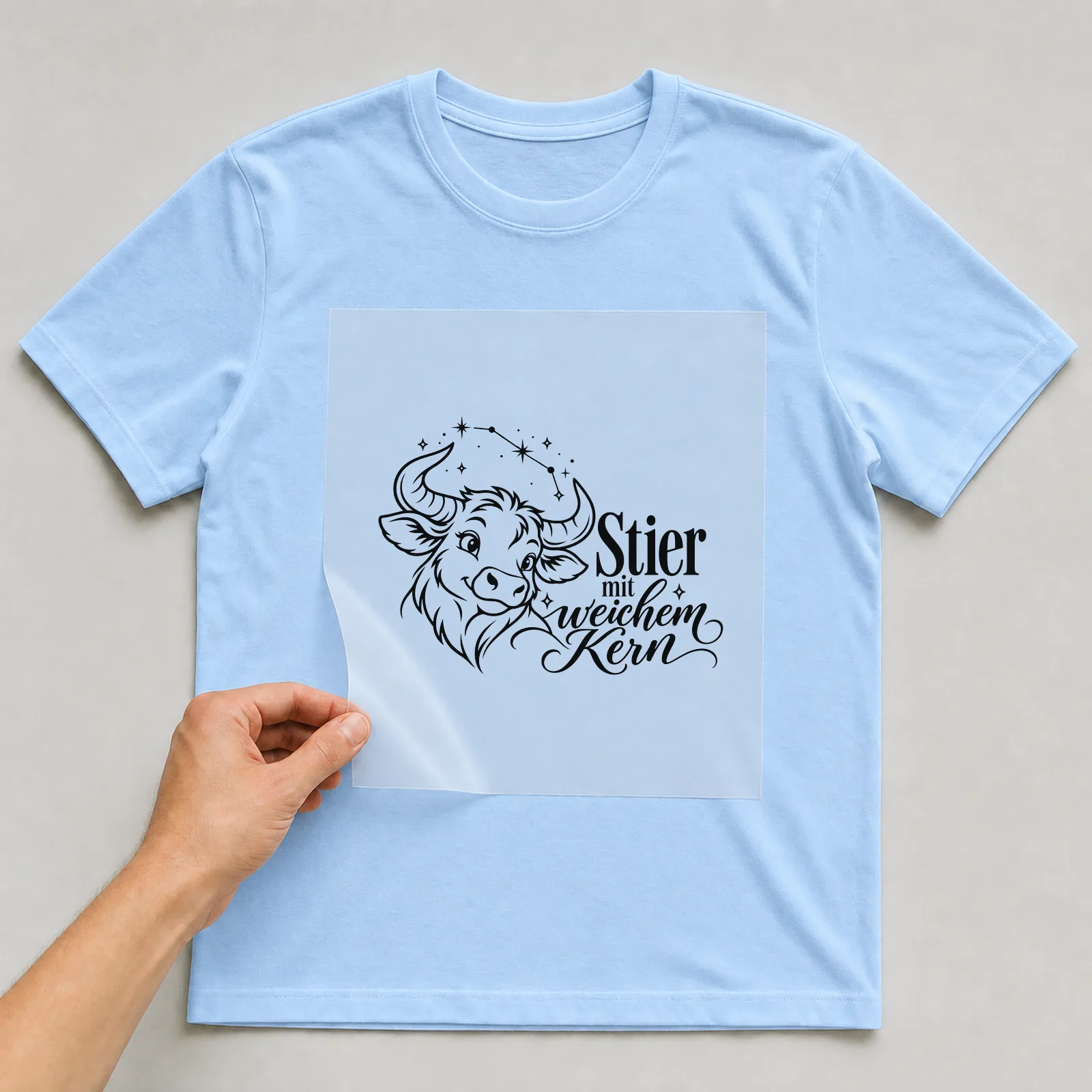 Bügelbild „Stier mit weichem Kern“ auf hellblauem T-Shirt, Folie wird aufgelegt
