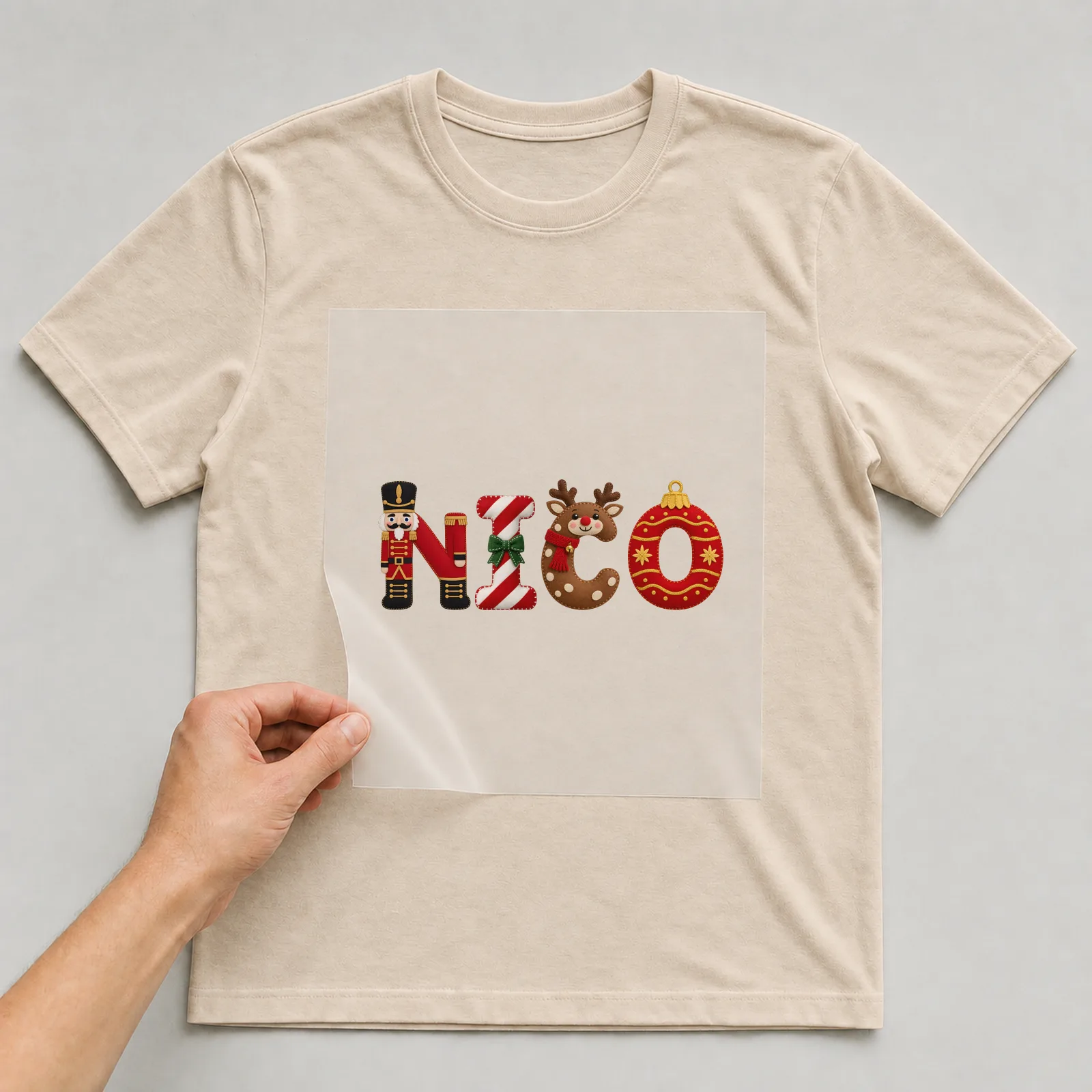 Bügelbild Weihnachtsbuchstaben mit Name auf beigem T-Shirt, Folie wird aufgelegt