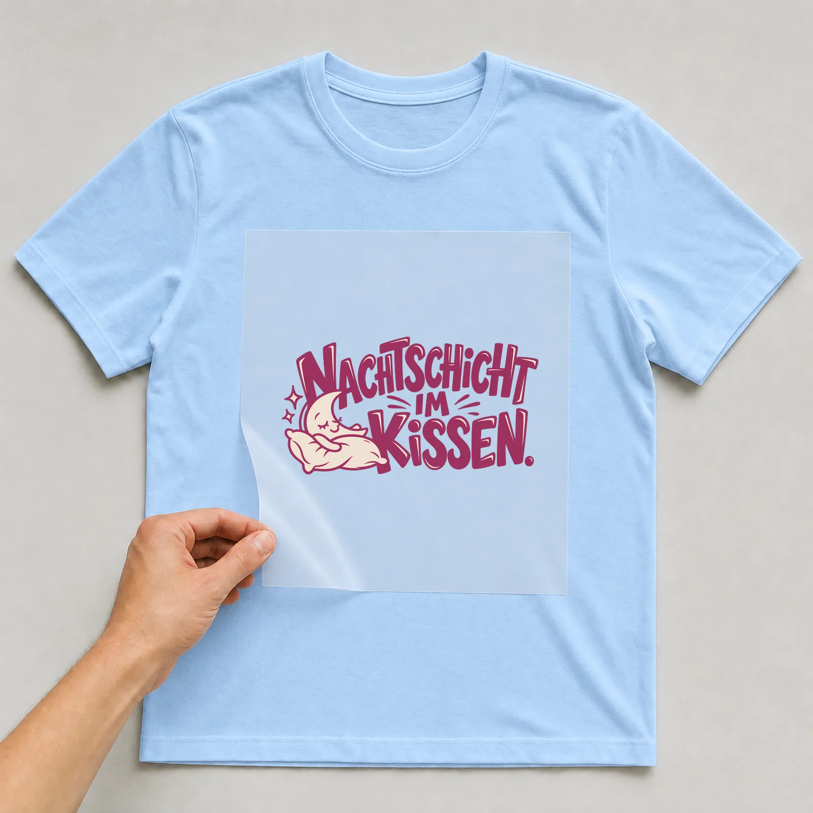 Bügelbild „Nachtschicht im Kissen“ auf hellblauem T-Shirt, Folie wird aufgelegt