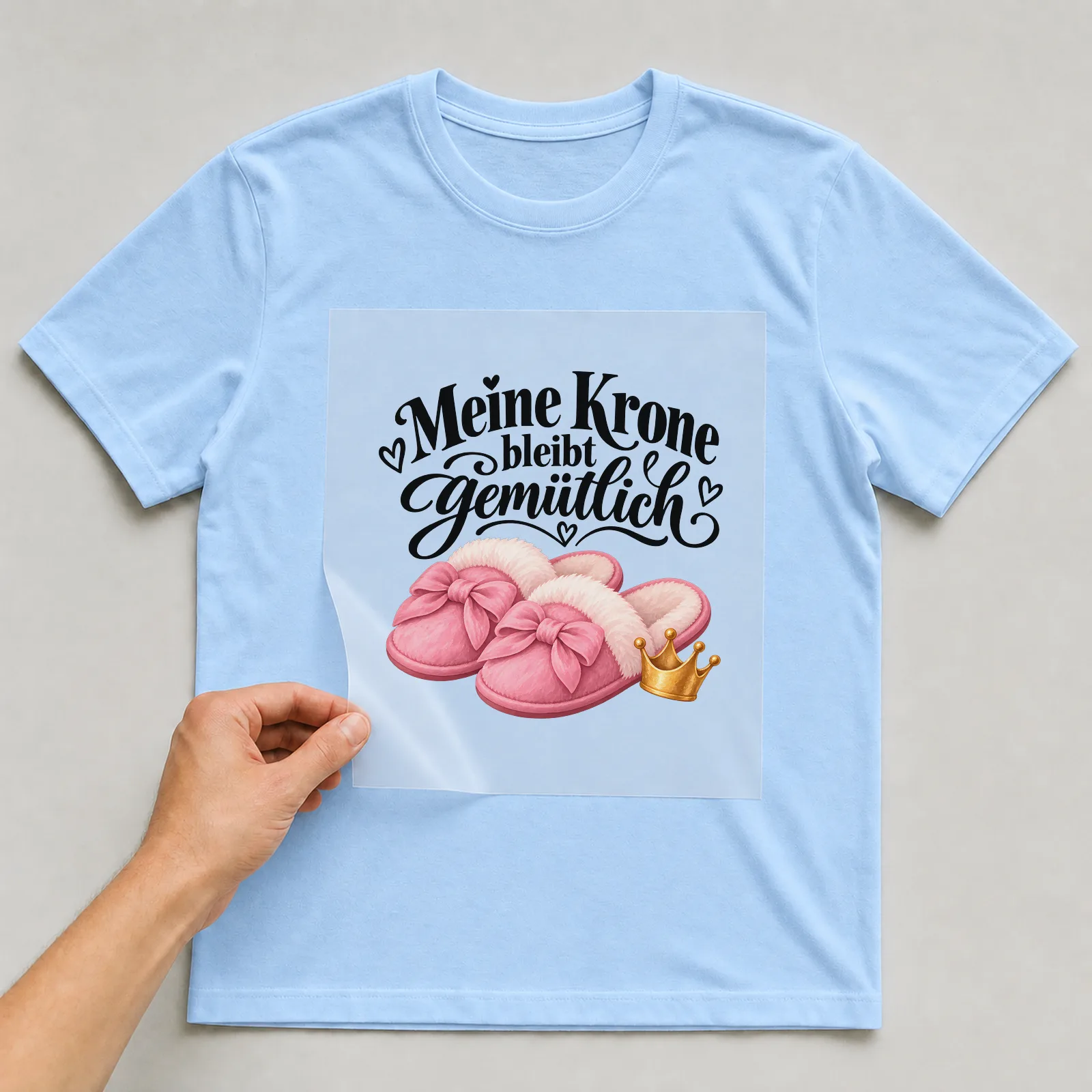 Bügelbild „Meine Krone bleibt gemütlich“ auf hellblauem T-Shirt, Folie wird aufgelegt