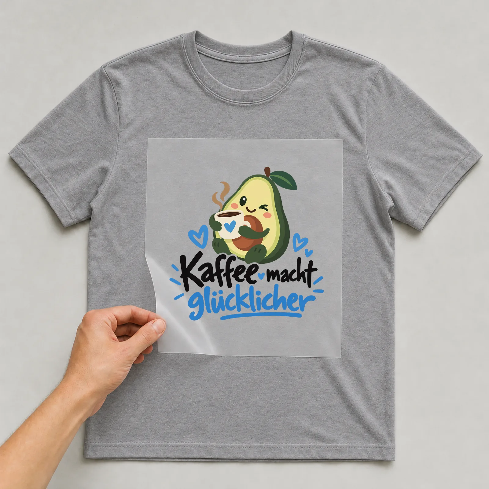 Bügelbild „Kaffee macht glücklicher“ (organischen Formen) auf grauem T-Shirt, Folie wird aufgelegt