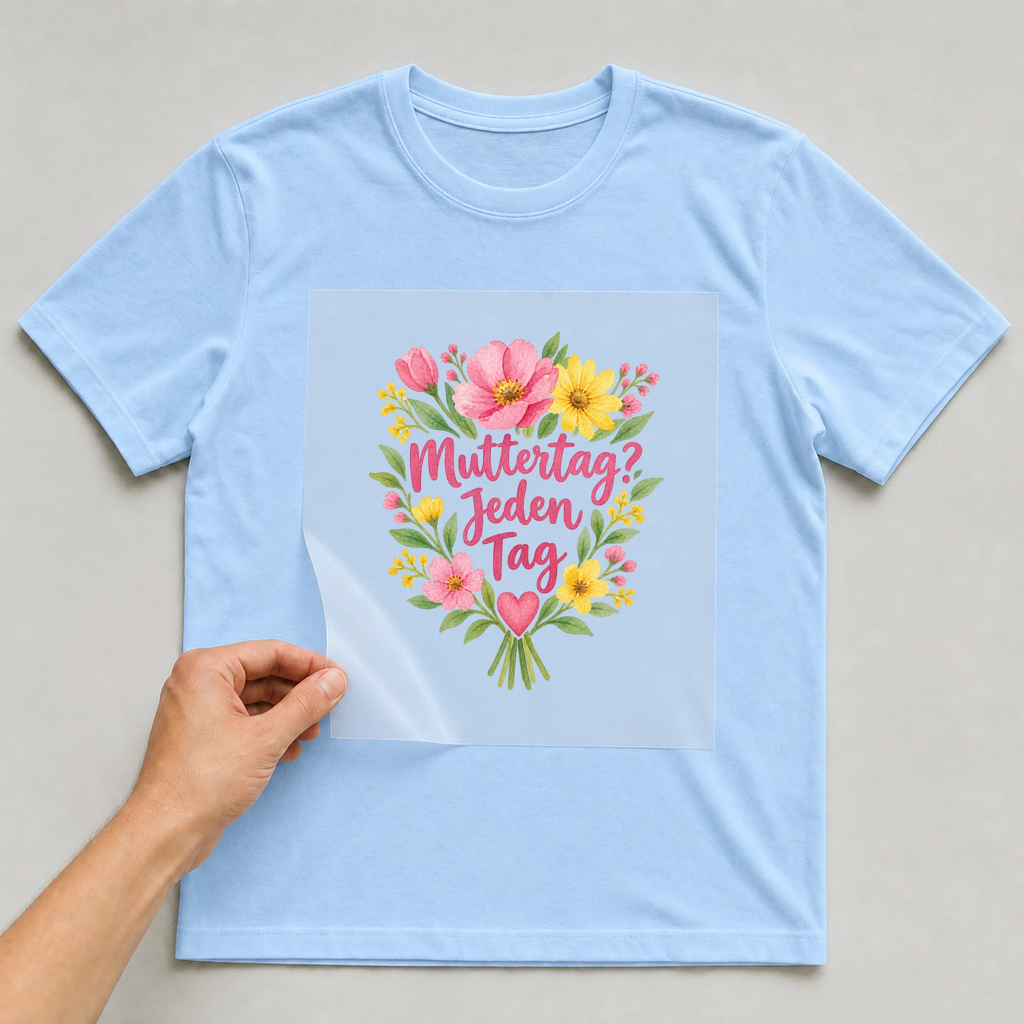 Bügelbild „Muttertag jeden tag“ auf babyblauem T-Shirt, Folie wird aufgelegt