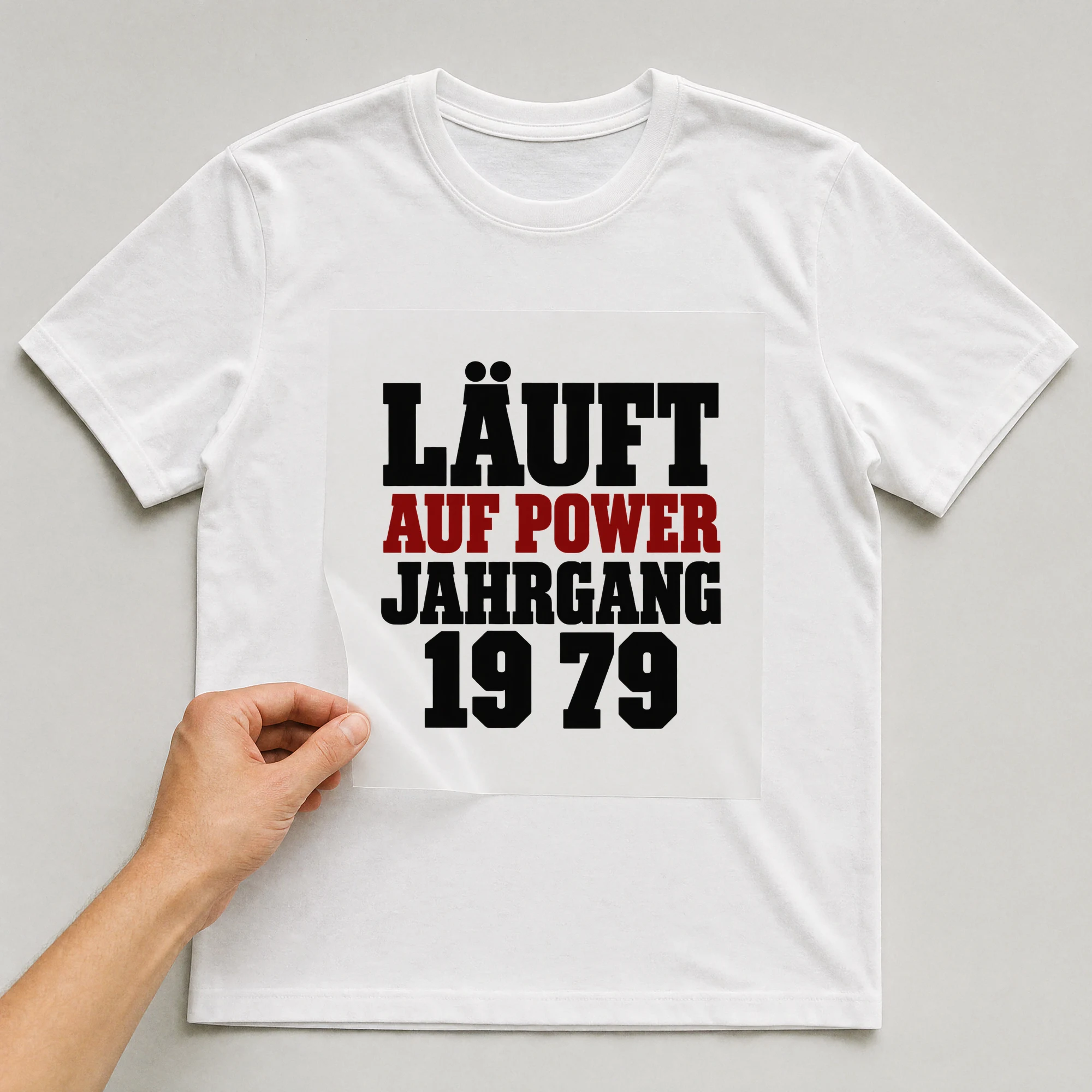 Bügelbild „Läuft auf Power, Jahrgang 1979“ auf weißem T-Shirt, Folie wird aufgelegt