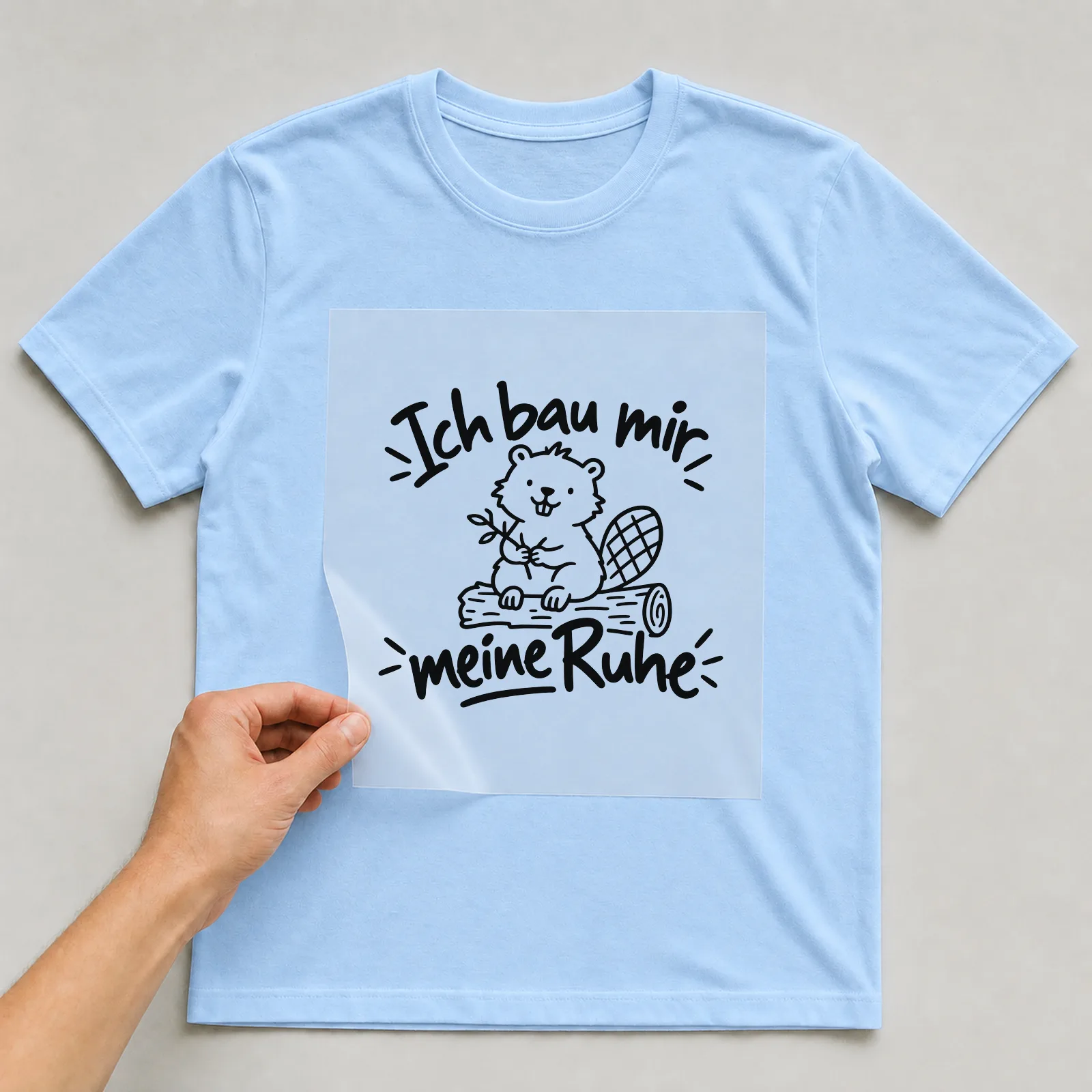 Bügelbild „Ich bau mir meine Ruhe“ auf hellblauem T-Shirt, Folie wird aufgelegt