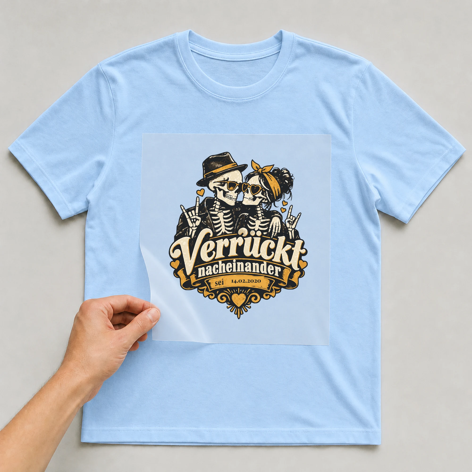 Bügelbild Verrückt nacheinander mit Datum auf hellblauem T-Shirt, Folie wird aufgelegt