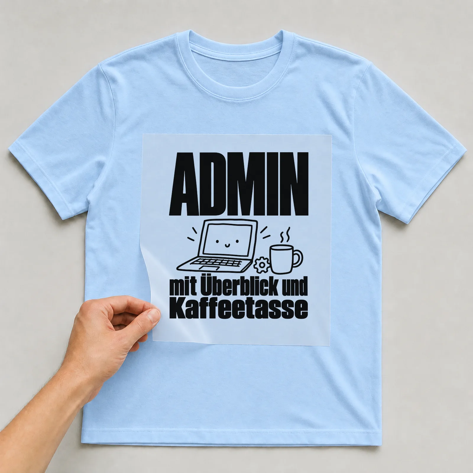Bügelbild „Admin mit Überblick und Kaffeetasse“ auf hellblauem T-Shirt, Folie wird aufgelegt