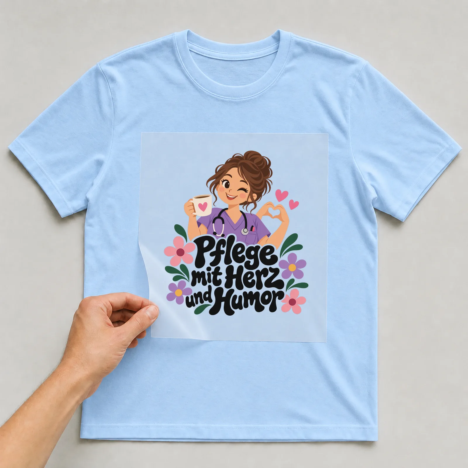 Bügelbild „Pflege mit Herz und Humor“ auf hellblauem T-Shirt, Folie wird aufgelegt
