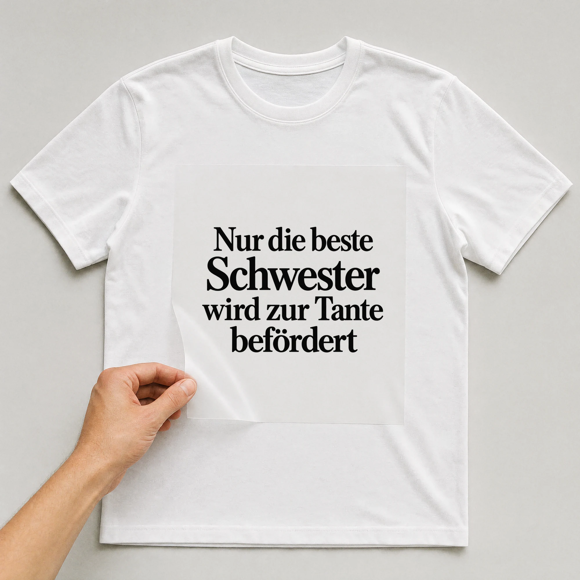 Bügelbild „Nur die beste Schwester wird zur Tante befördert“ auf weißem T-Shirt, Folie wird aufgelegt