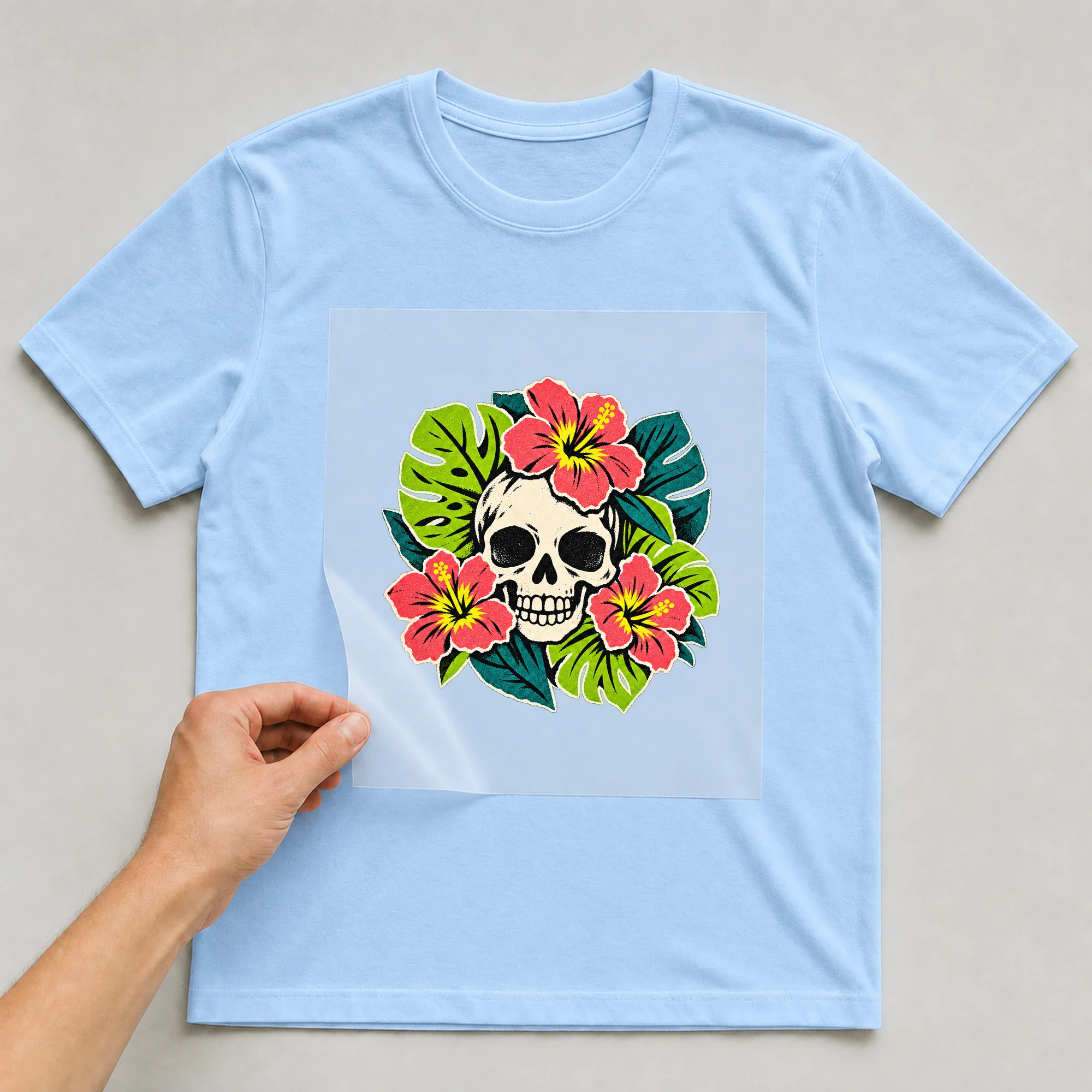 Bügelbild „Totenkopf Collage Brasilien“ auf babyblauem T-Shirt, Folie wird aufgelegt
