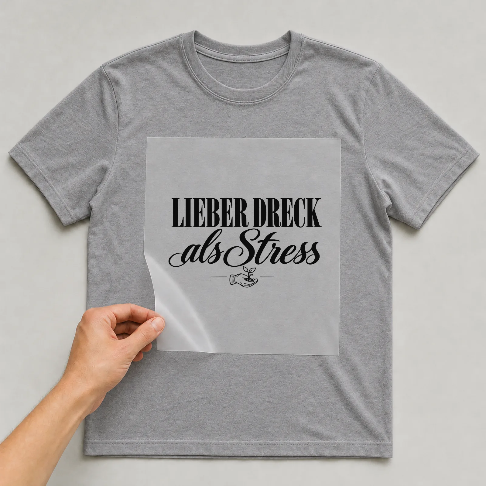 Bügelbild „Lieber Dreck als Stress“ auf grauem T-Shirt, Folie wird aufgelegt