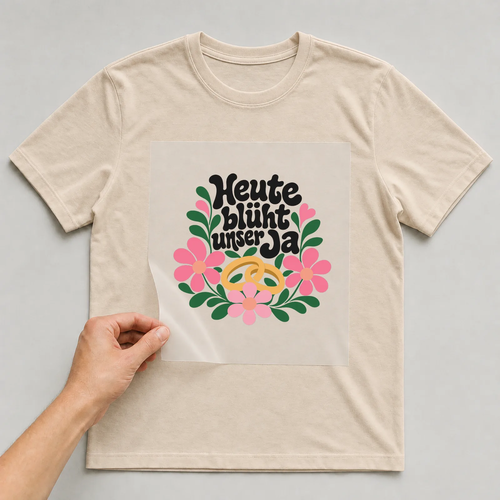 Bügelbild „Heute blüht unser Ja“ auf beigem T-Shirt, Folie wird aufgelegt