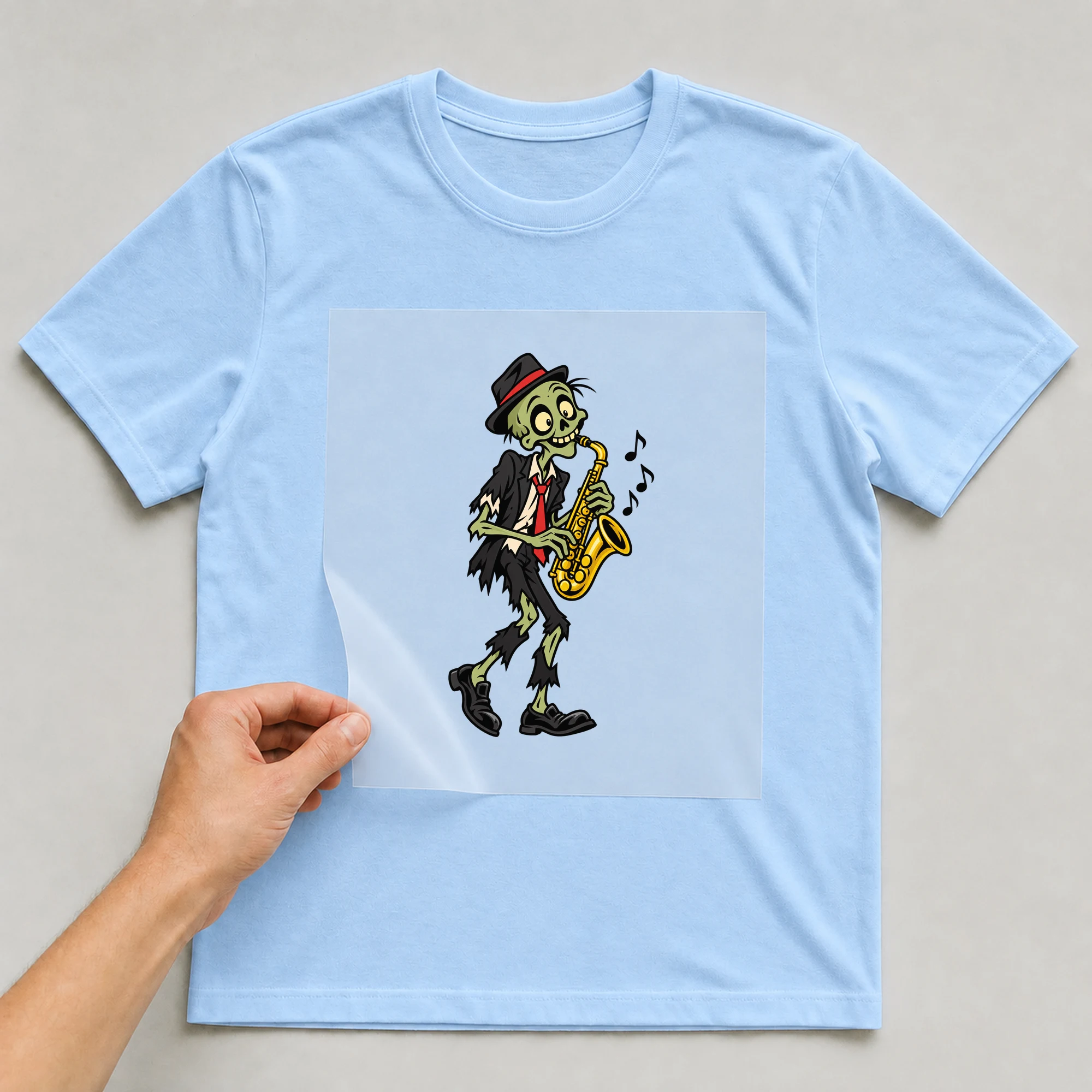 Bügelbild „Musizierender Zombie“ auf babyblauem T-Shirt, Folie wird aufgelegt