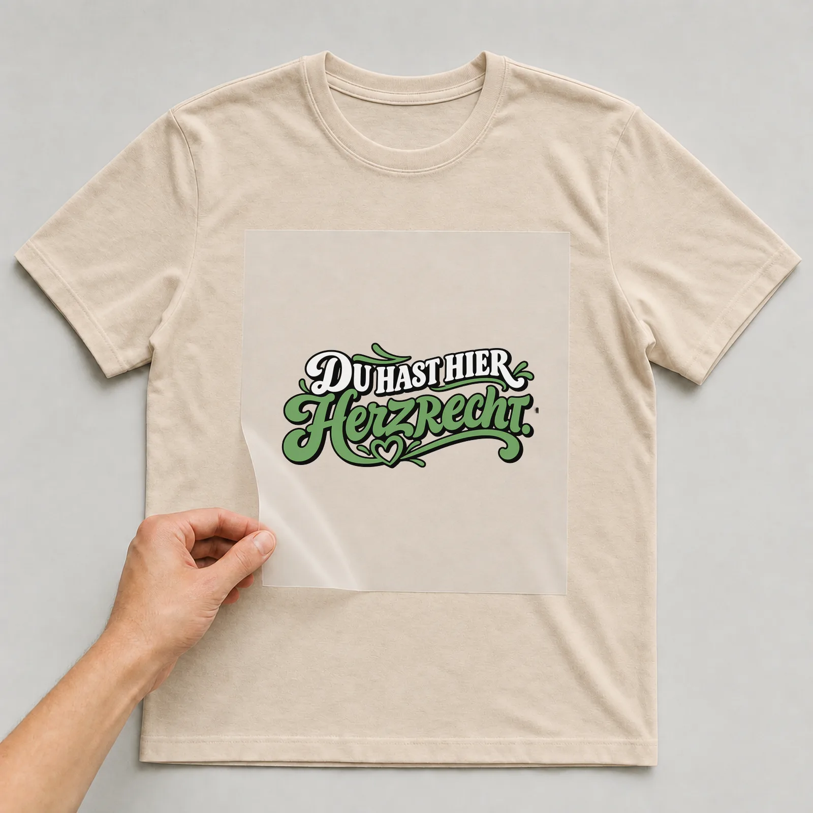 Bügelbild „Du hast hier Herzrecht“ auf beigem T-Shirt, Folie wird aufgelegt