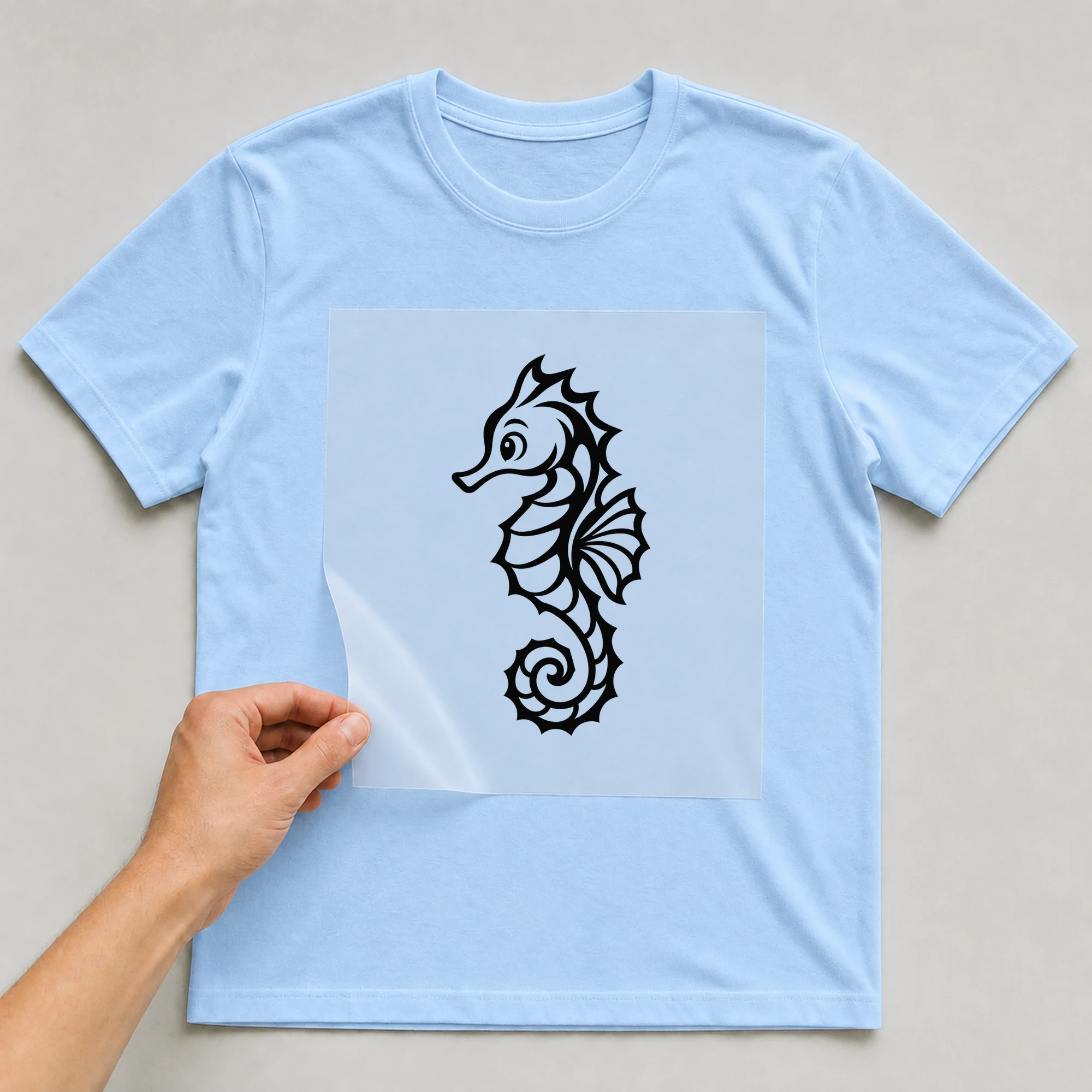 Bügelbild „BB021148-motiv-r03659“ auf babyblauem T-Shirt, Folie wird aufgelegt
