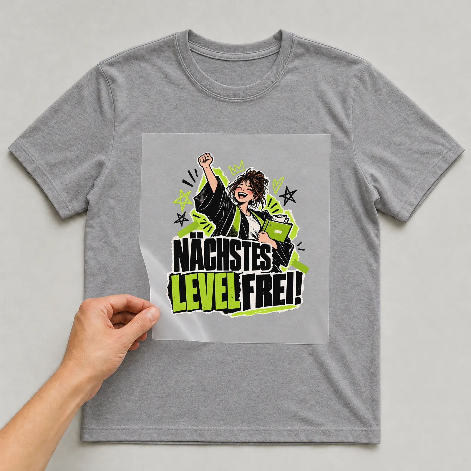 Bügelbild „Nächstes Level frei!“ auf grauem T-Shirt, Folie wird aufgelegt