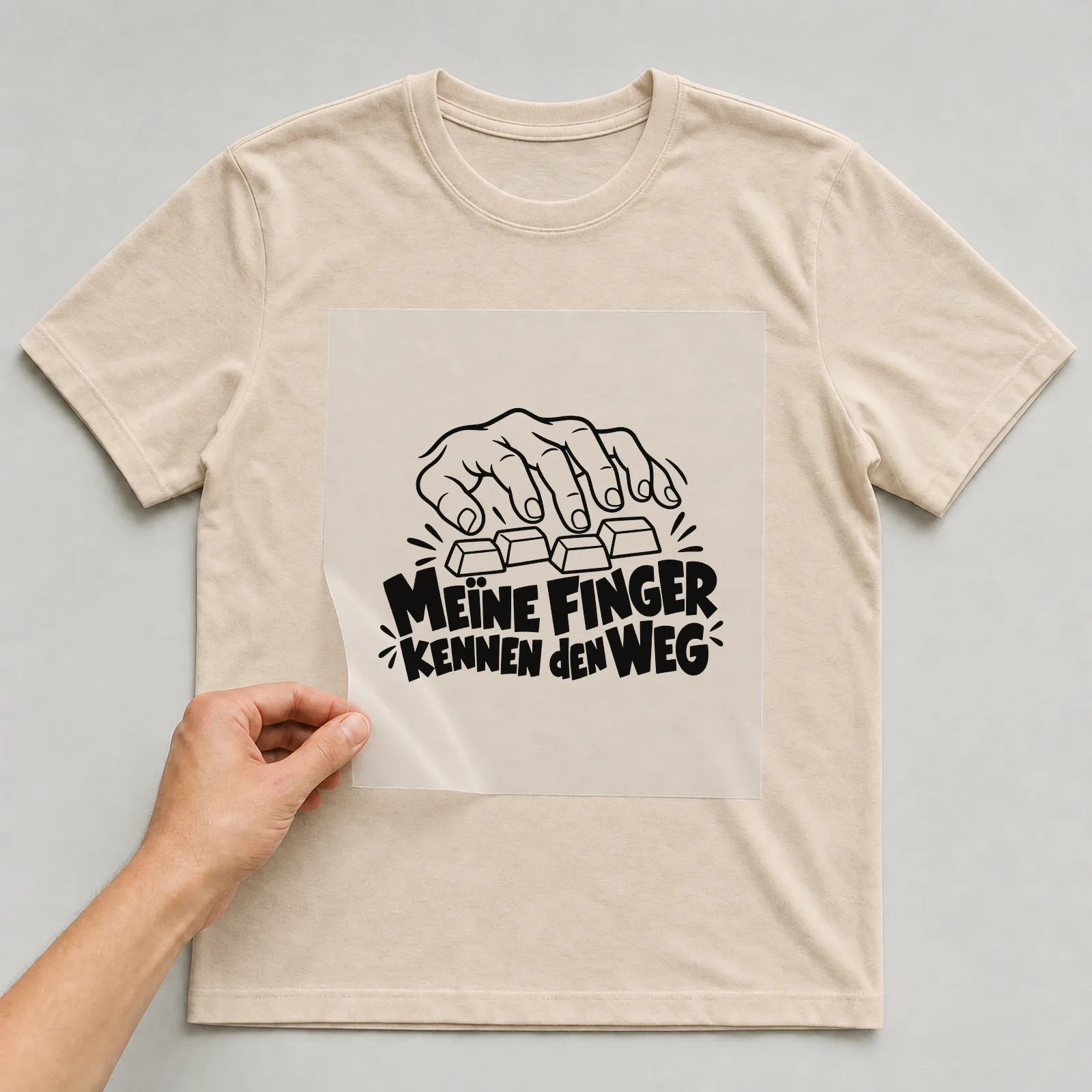 Bügelbild „Meine Finger kennen den Weg“ auf beigem T-Shirt, Folie wird aufgelegt