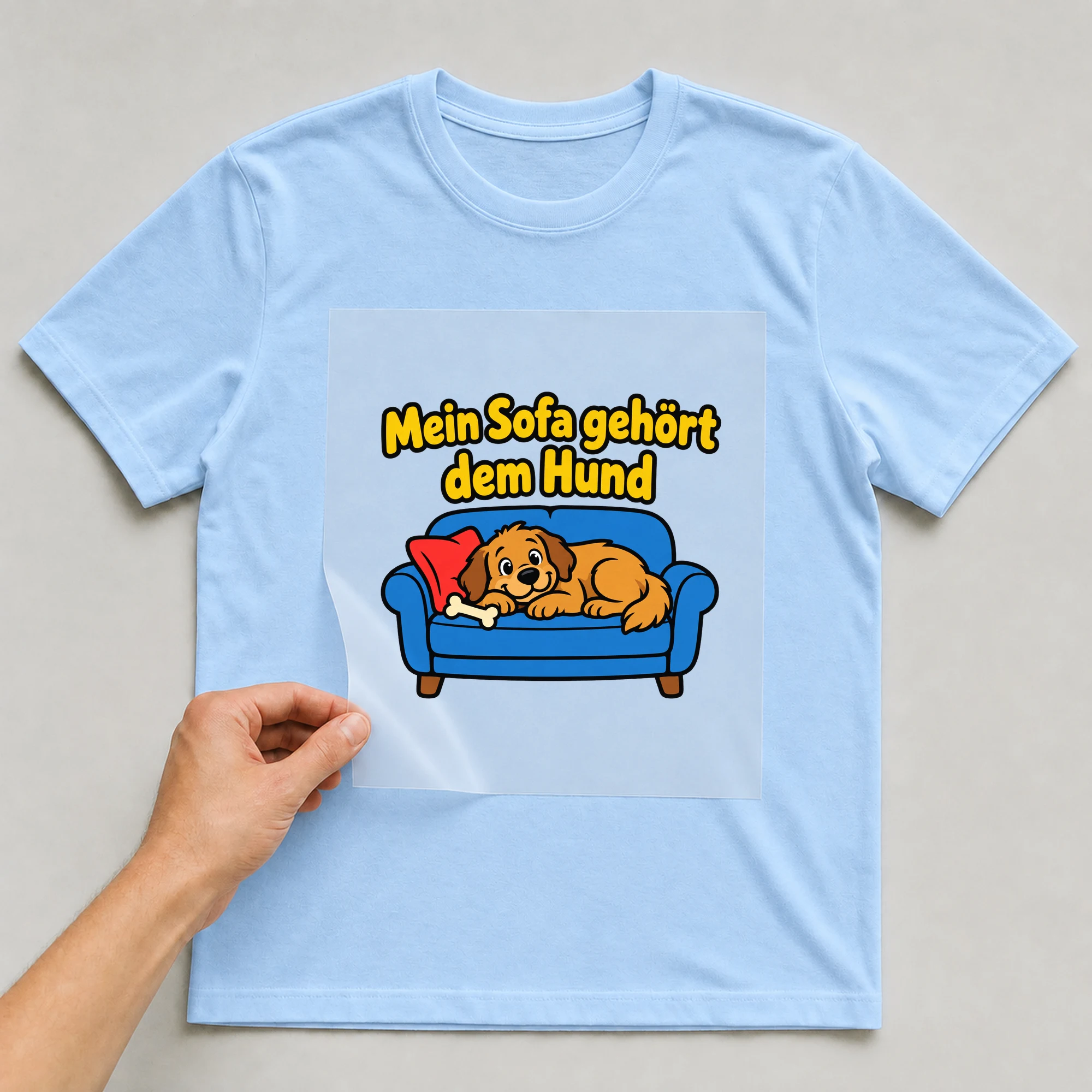 Bügelbild „Mein Sofa gehört dem Hund“ auf babyblauem T-Shirt, Folie wird aufgelegt