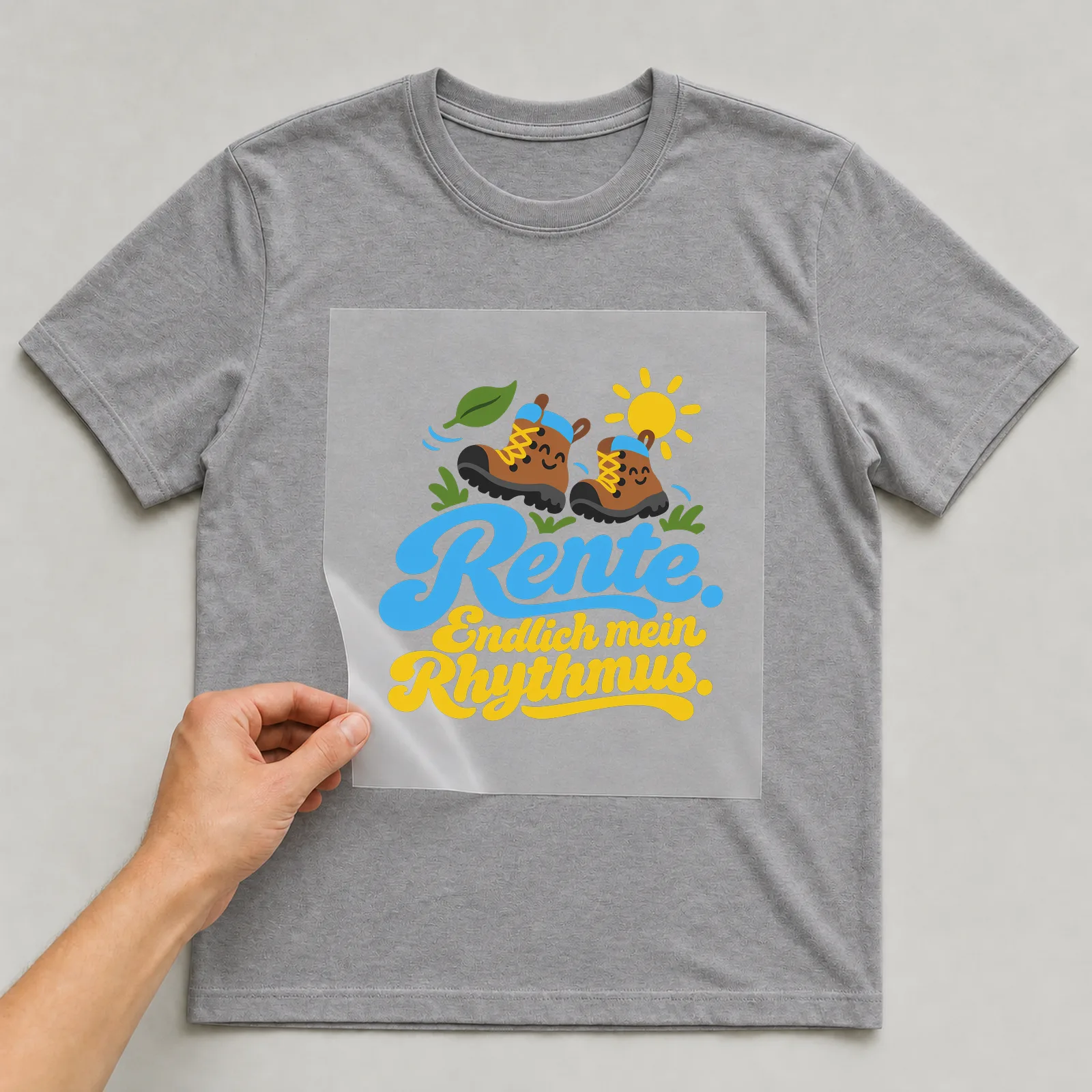 Bügelbild „Rente. Endlich mein Rhythmus.“ auf grauem T-Shirt, Folie wird aufgelegt