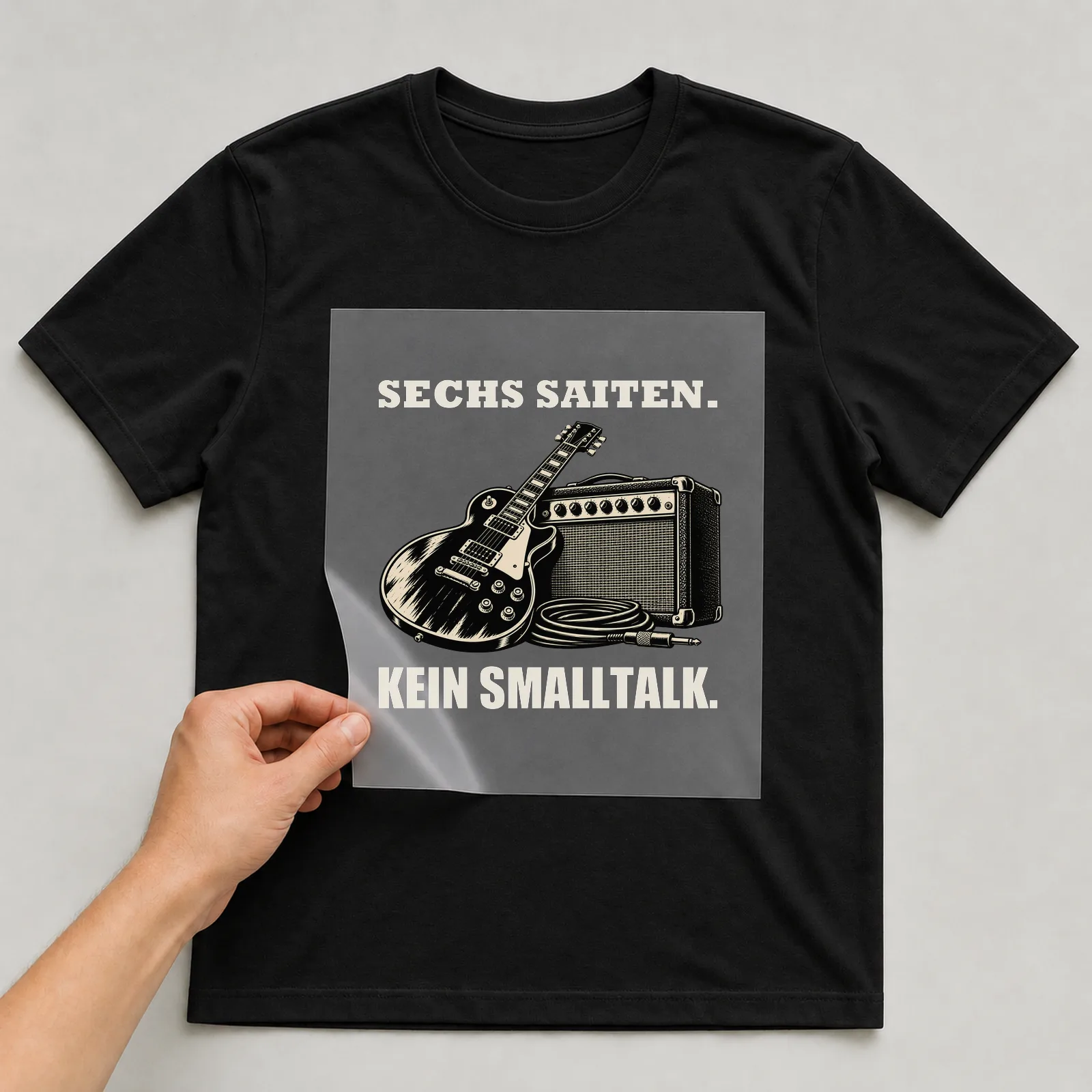 Bügelbild „Sechs Saiten. Kein Smalltalk.“ auf schwarzem T-Shirt, Folie wird aufgelegt