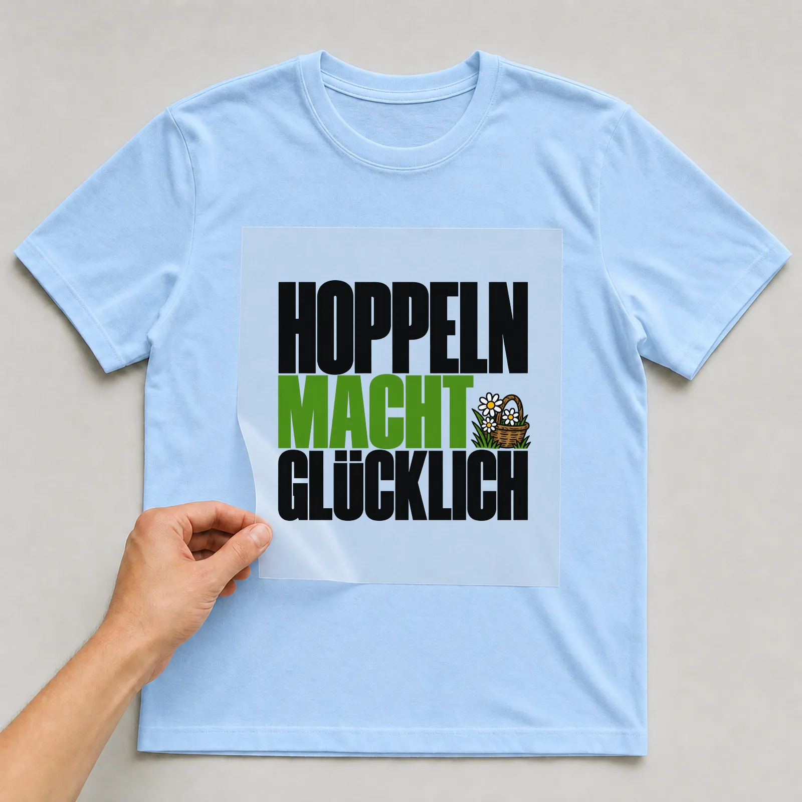 Bügelbild „Hoppeln macht glücklich“ auf hellblauem T-Shirt, Folie wird aufgelegt