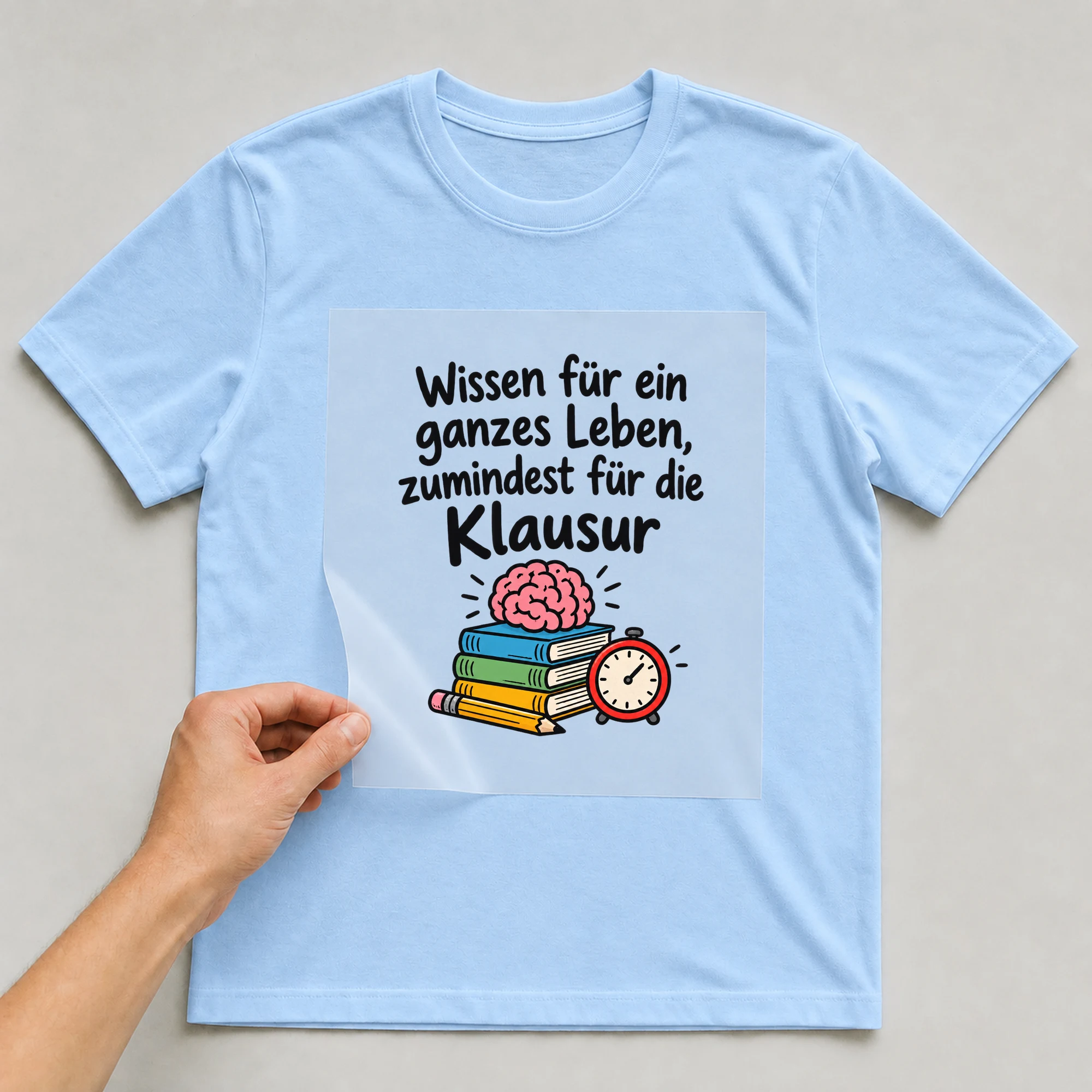 Bügelbild „Wissen für ein ganzes Leben, zumindest für die Klausur“ auf babyblauem T-Shirt, Folie wird aufgelegt