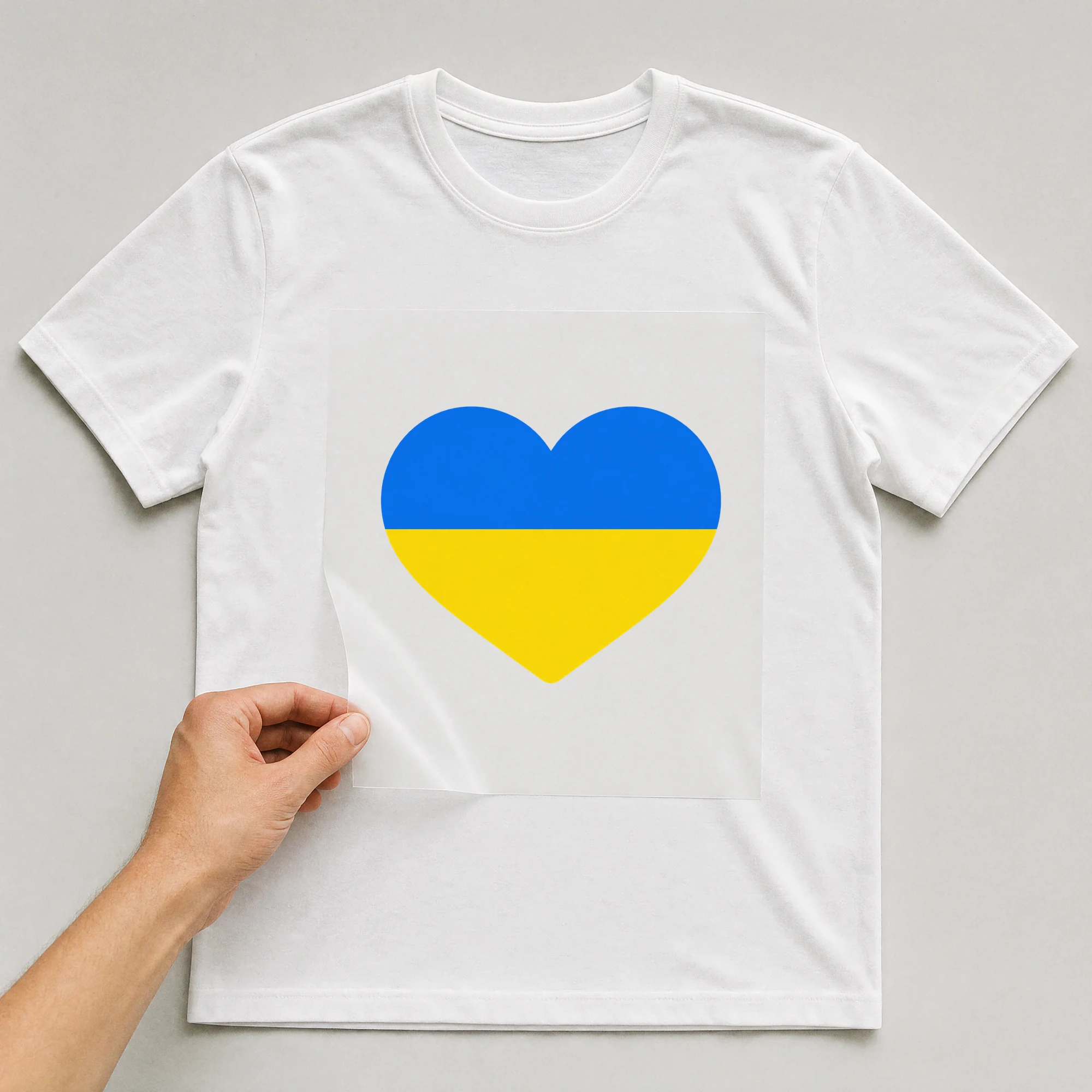 Bügelbild „Ukraine Herz“ auf weißem T-Shirt, Folie wird aufgelegt