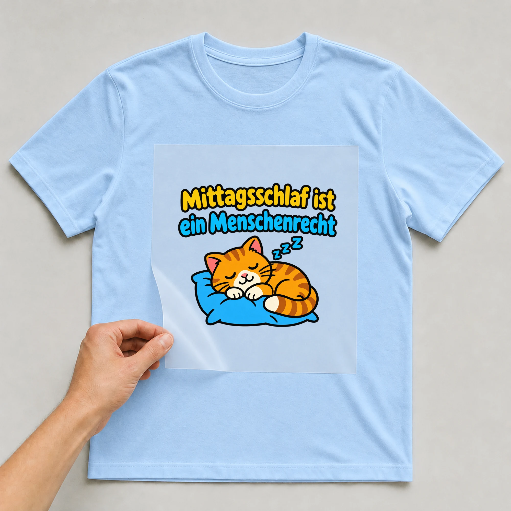 Bügelbild „Mittagsschlaf ist ein Menschenrecht“ auf babyblauem T-Shirt, Folie wird aufgelegt
