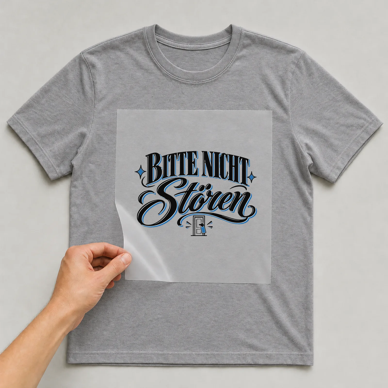 Bügelbild „Bitte nicht stören“ auf grauem T-Shirt, Folie wird aufgelegt