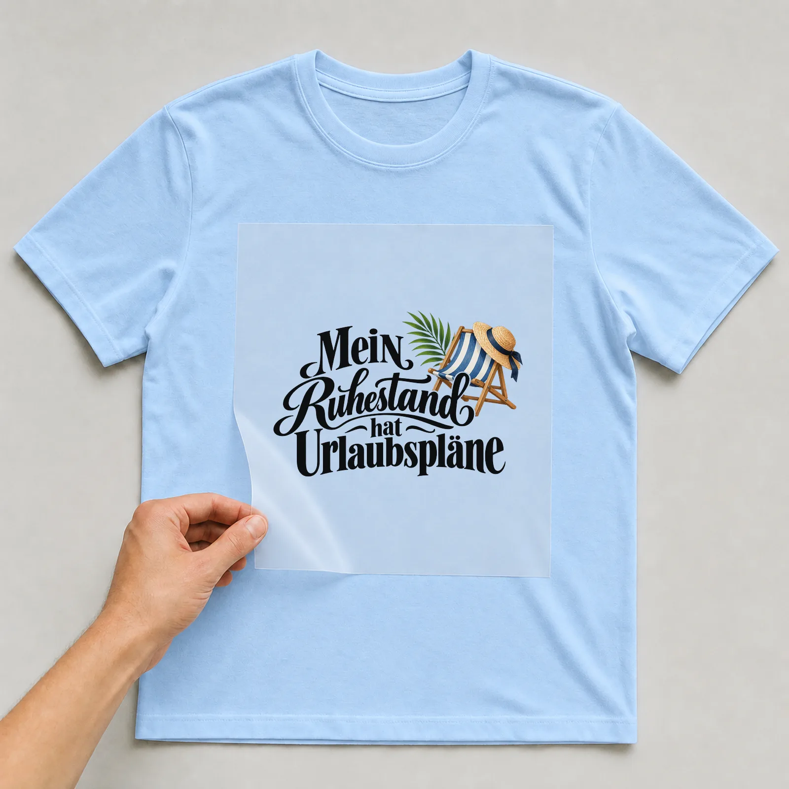 Bügelbild „Mein Ruhestand hat Urlaubspläne“ auf hellblauem T-Shirt, Folie wird aufgelegt