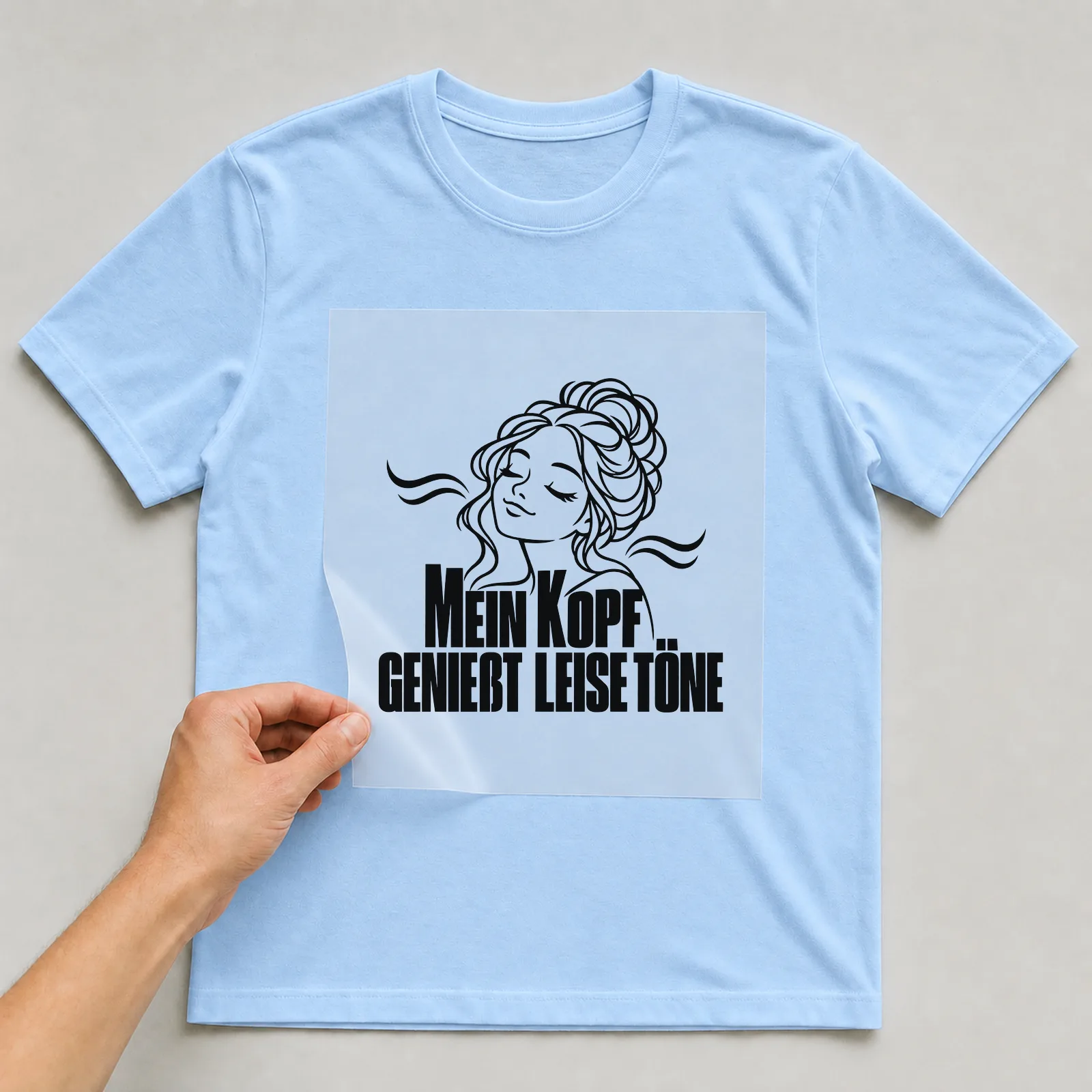 Bügelbild „Mein Kopf genießt leise töne“ auf hellblauem T-Shirt, Folie wird aufgelegt