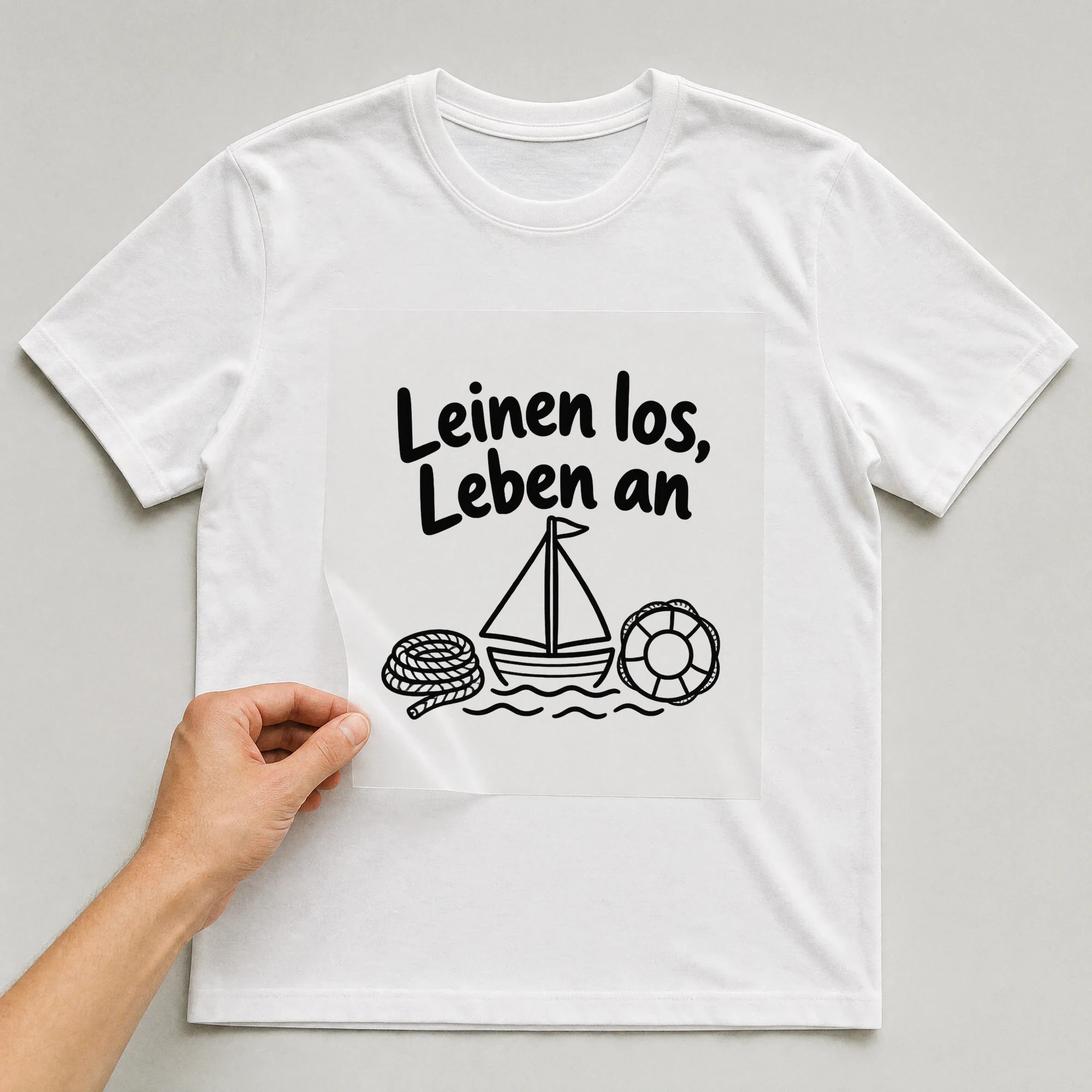 Bügelbild „Leinen los, Leben an“ auf weißem T-Shirt, Folie wird aufgelegt