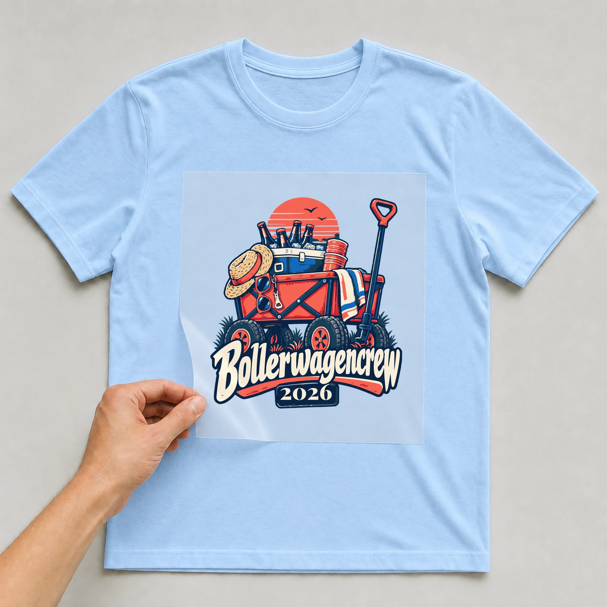 Bügelbild Bollerwagencrew mit Jahr auf hellblauem T-Shirt, Folie wird aufgelegt
