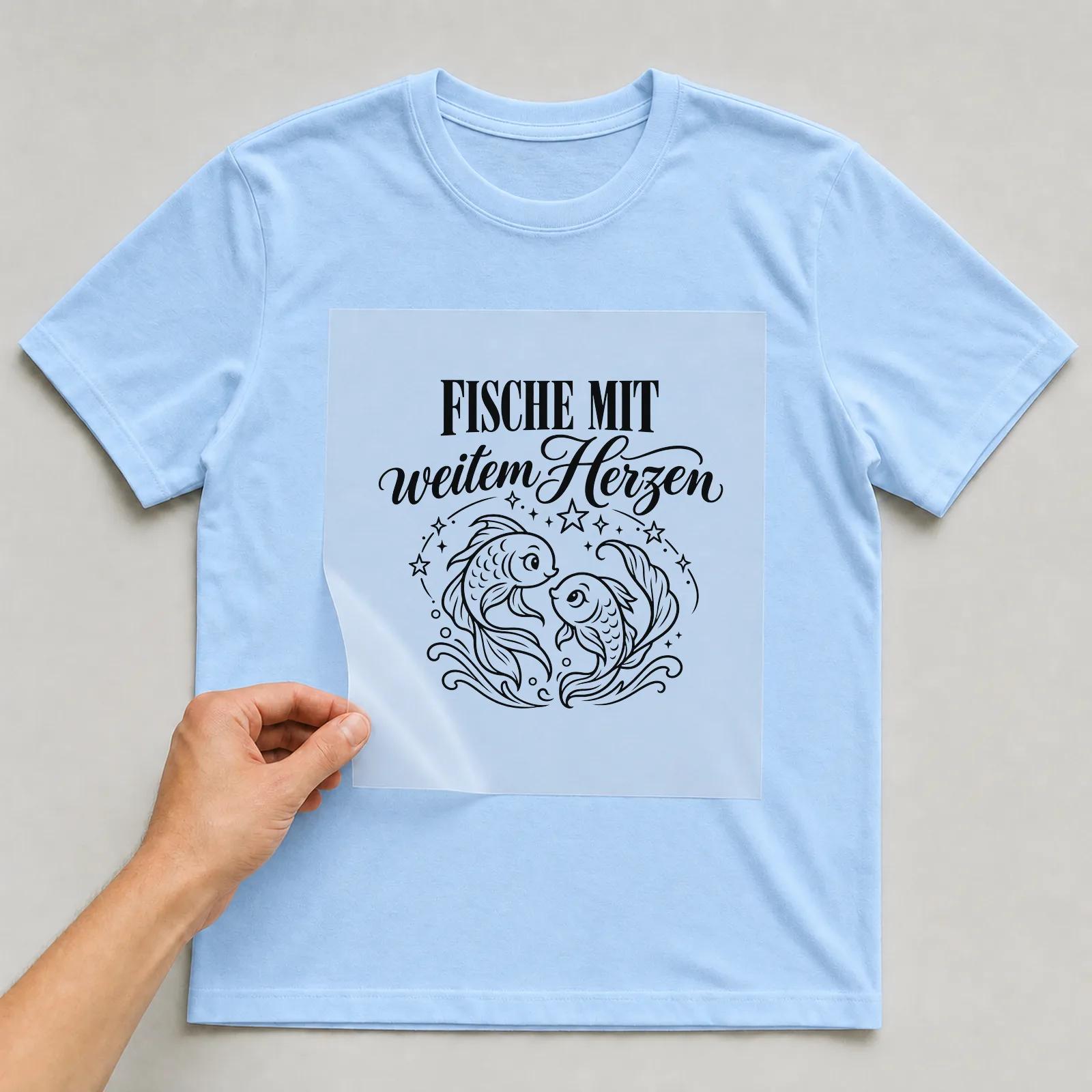 Bügelbild „Fische mit weitem Herzen“ auf hellblauem T-Shirt, Folie wird aufgelegt