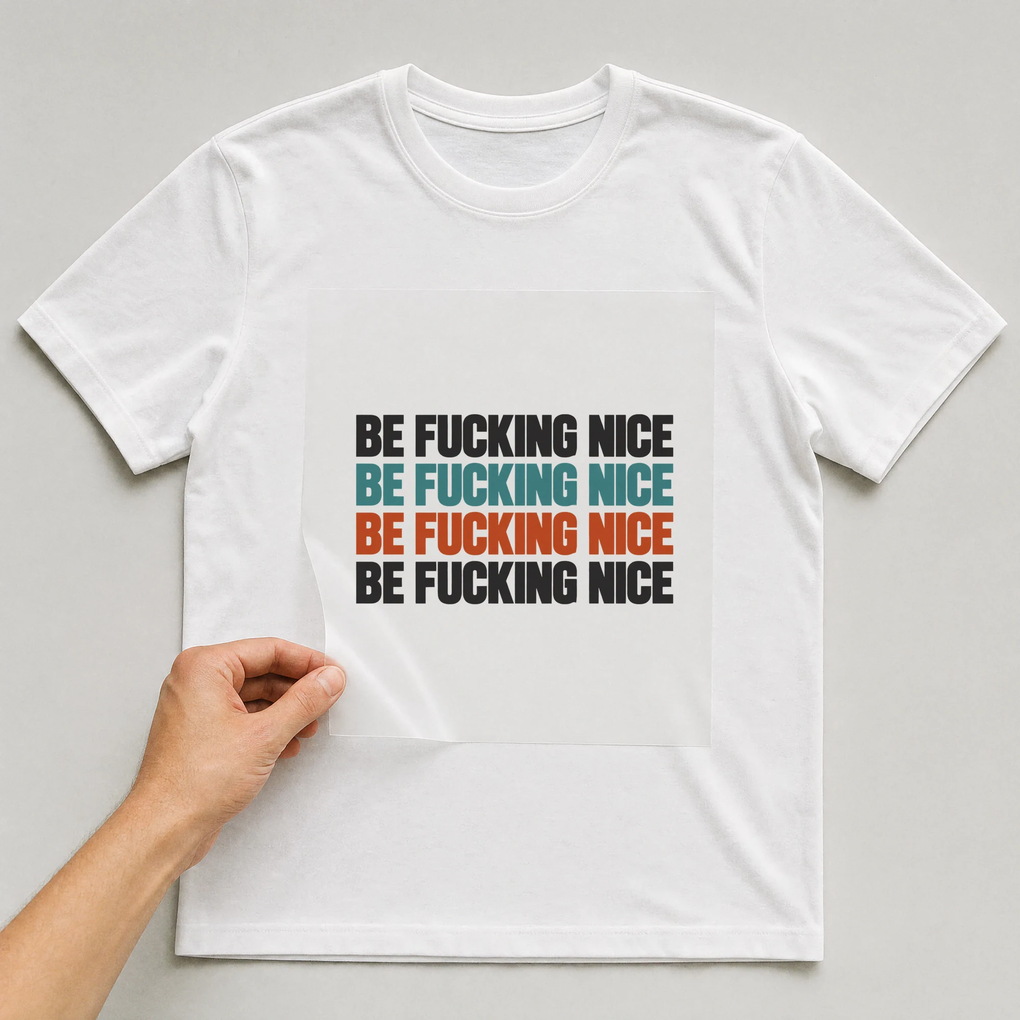 Bügelbild „Be F*cking Nice Be F*cking Nice Be F*cking Nice Be F*cking Nice“ auf weißem T-Shirt, Folie wird aufgelegt
