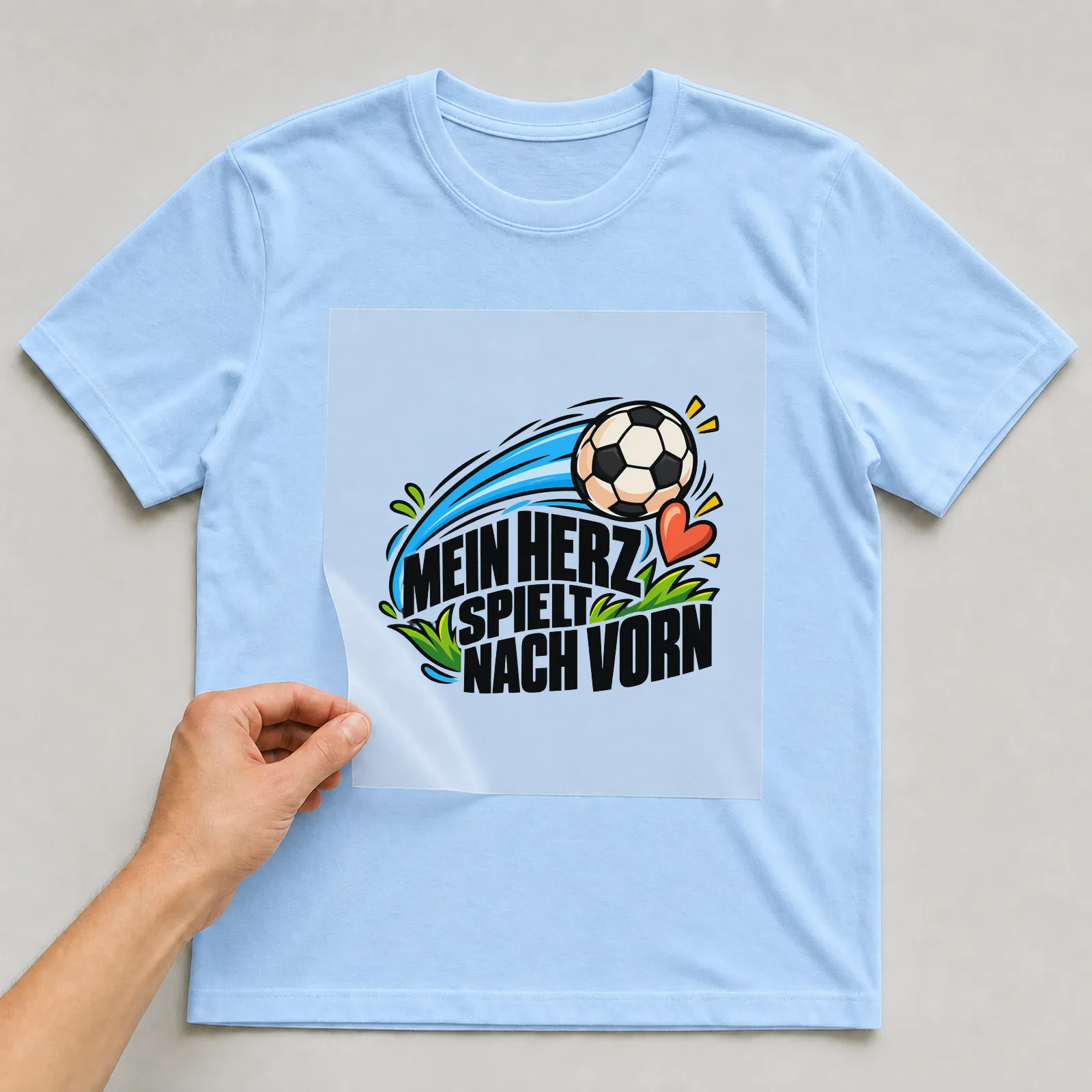 Bügelbild „Mein Herz spielt nach Vorn“ auf hellblauem T-Shirt, Folie wird aufgelegt