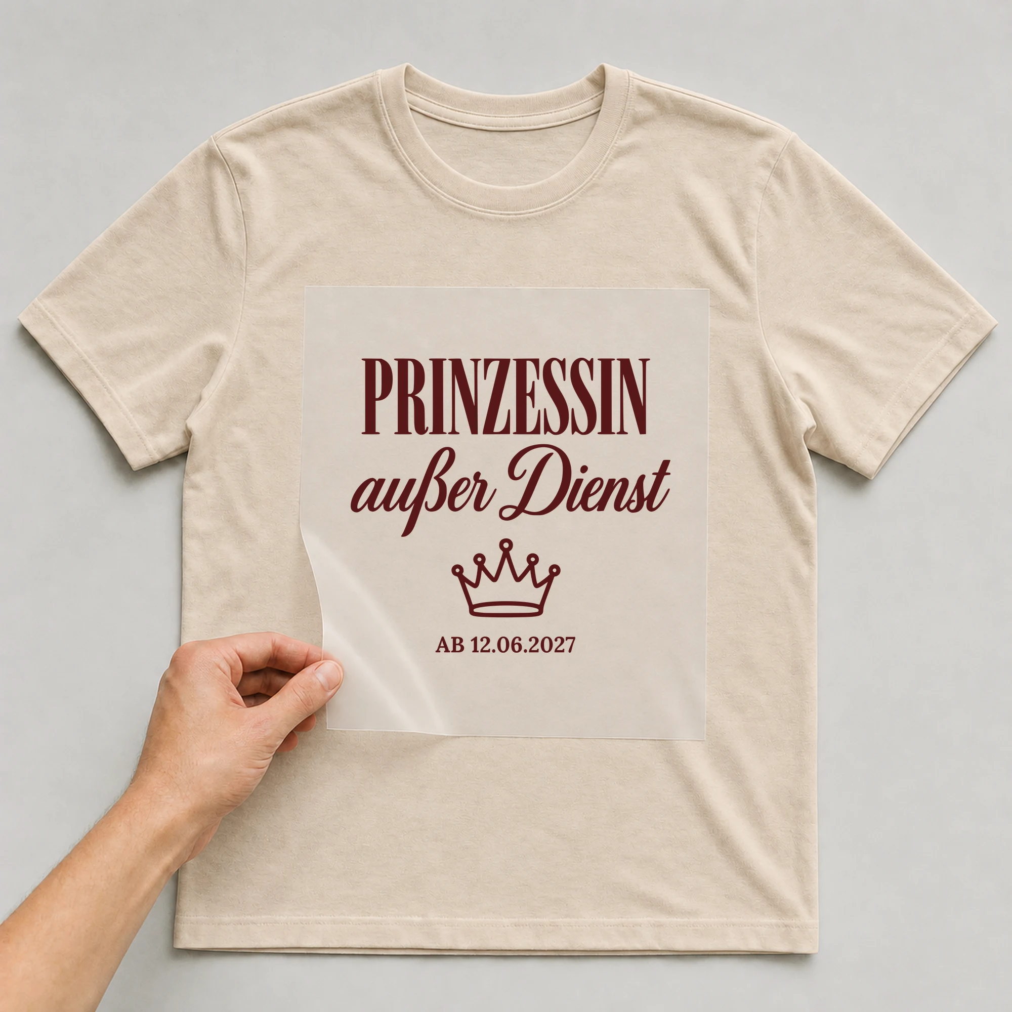 Bügelbild Prinzessin außer Dienst mit Datum auf beigem T-Shirt, Folie wird aufgelegt