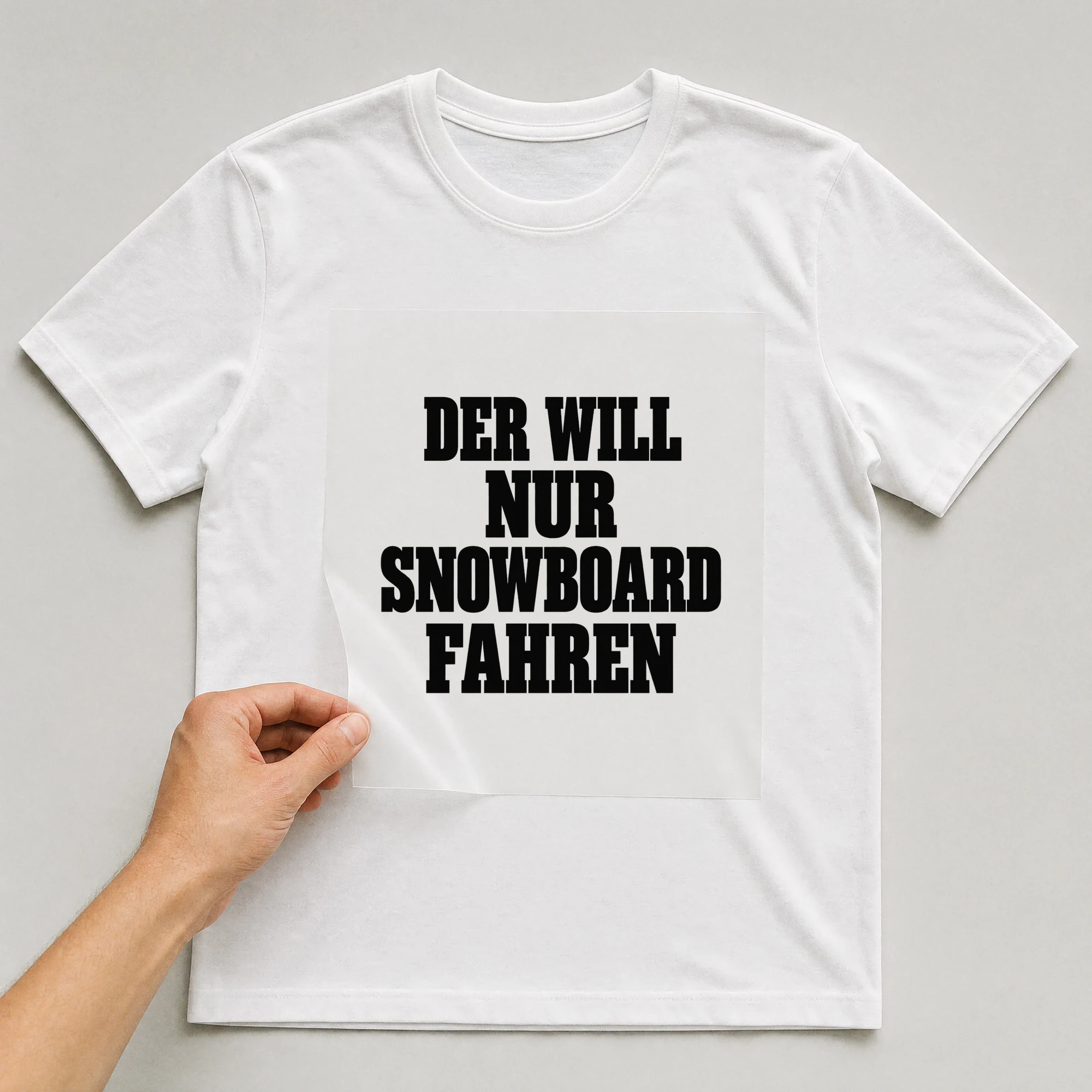 Bügelbild „Der will nur Snowboard fahren“ auf weißem T-Shirt, Folie wird aufgelegt