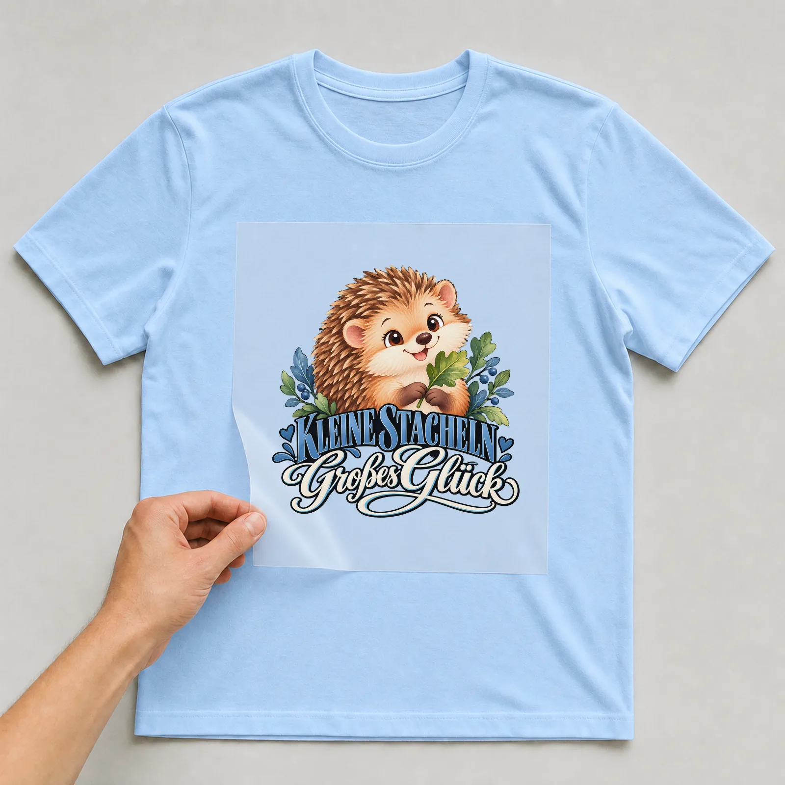 Bügelbild „Kleine Stacheln Großes Glück“ (deckendem Aquarell) auf hellblauem T-Shirt, Folie wird aufgelegt