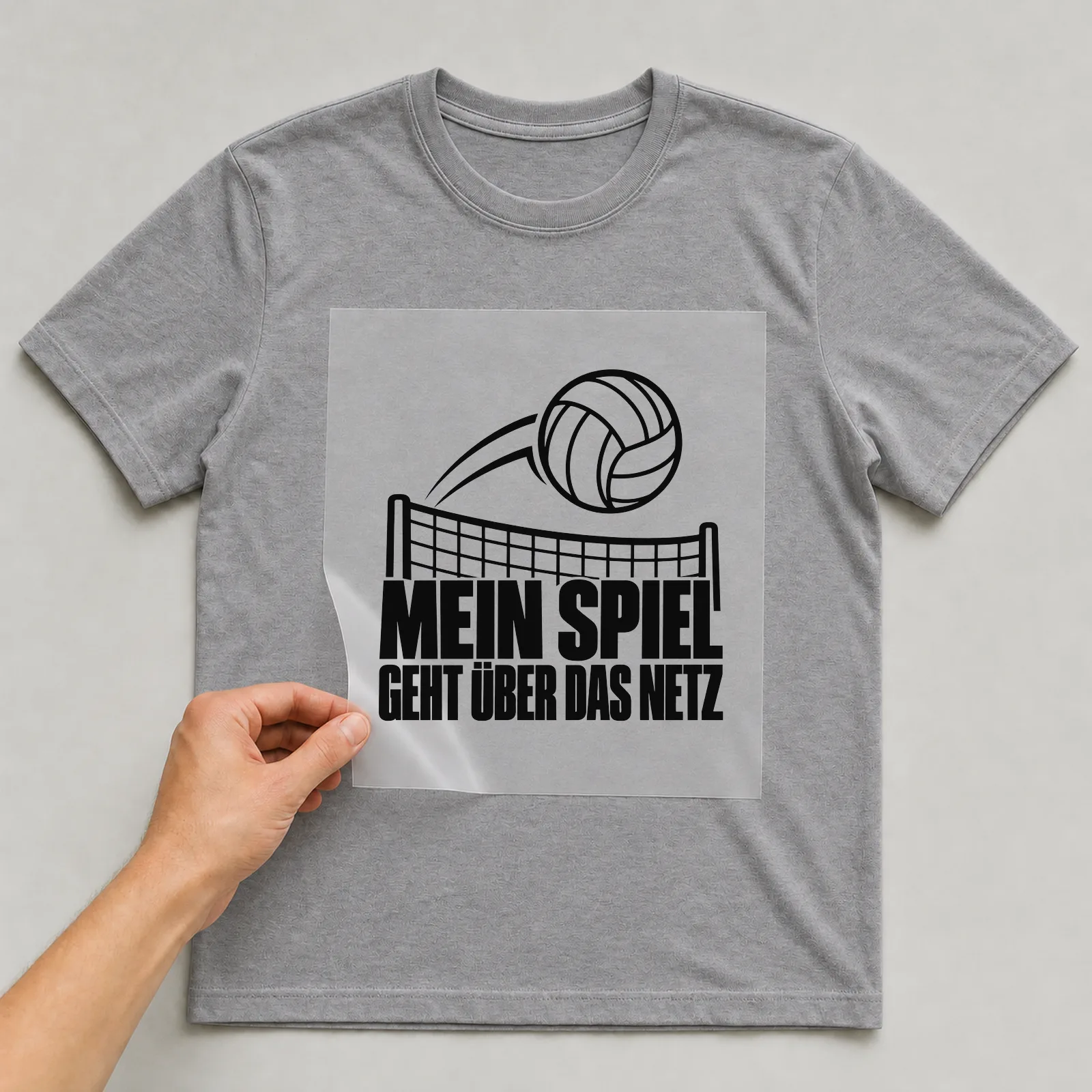 Bügelbild „Mein Spiel geht über das Netz“ auf grauem T-Shirt, Folie wird aufgelegt