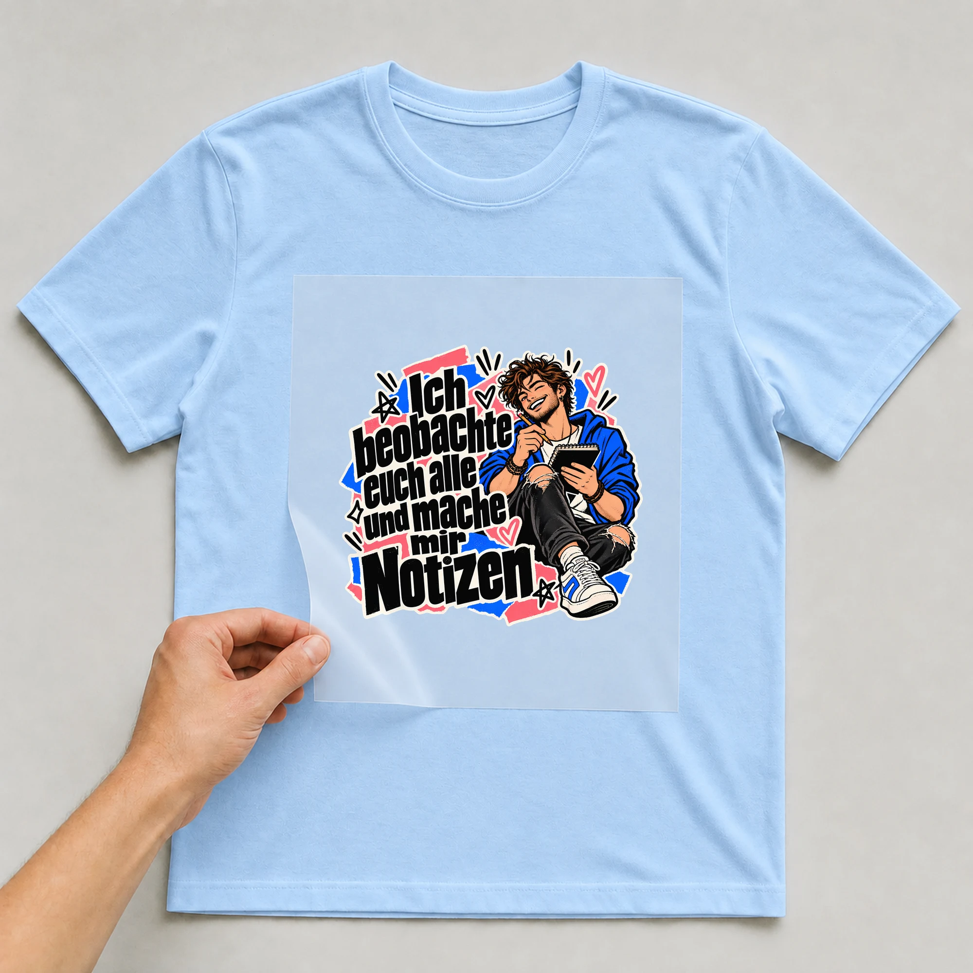 Bügelbild „Ich beobachte euch alle und mache mir Notizen“ auf babyblauem T-Shirt, Folie wird aufgelegt