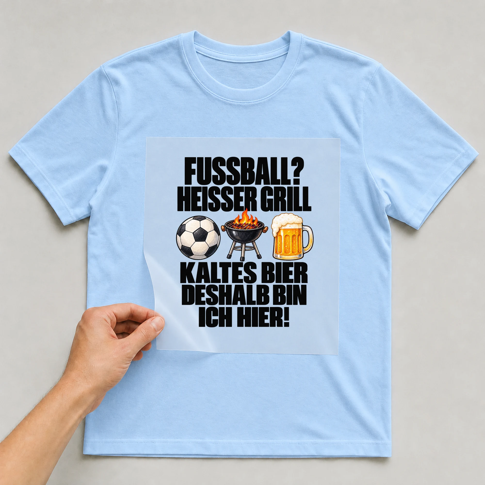 Bügelbild „Fußball? Heißer Grill kaltes Bier deshalb bin ich hier!“ auf babyblauem T-Shirt, Folie wird aufgelegt