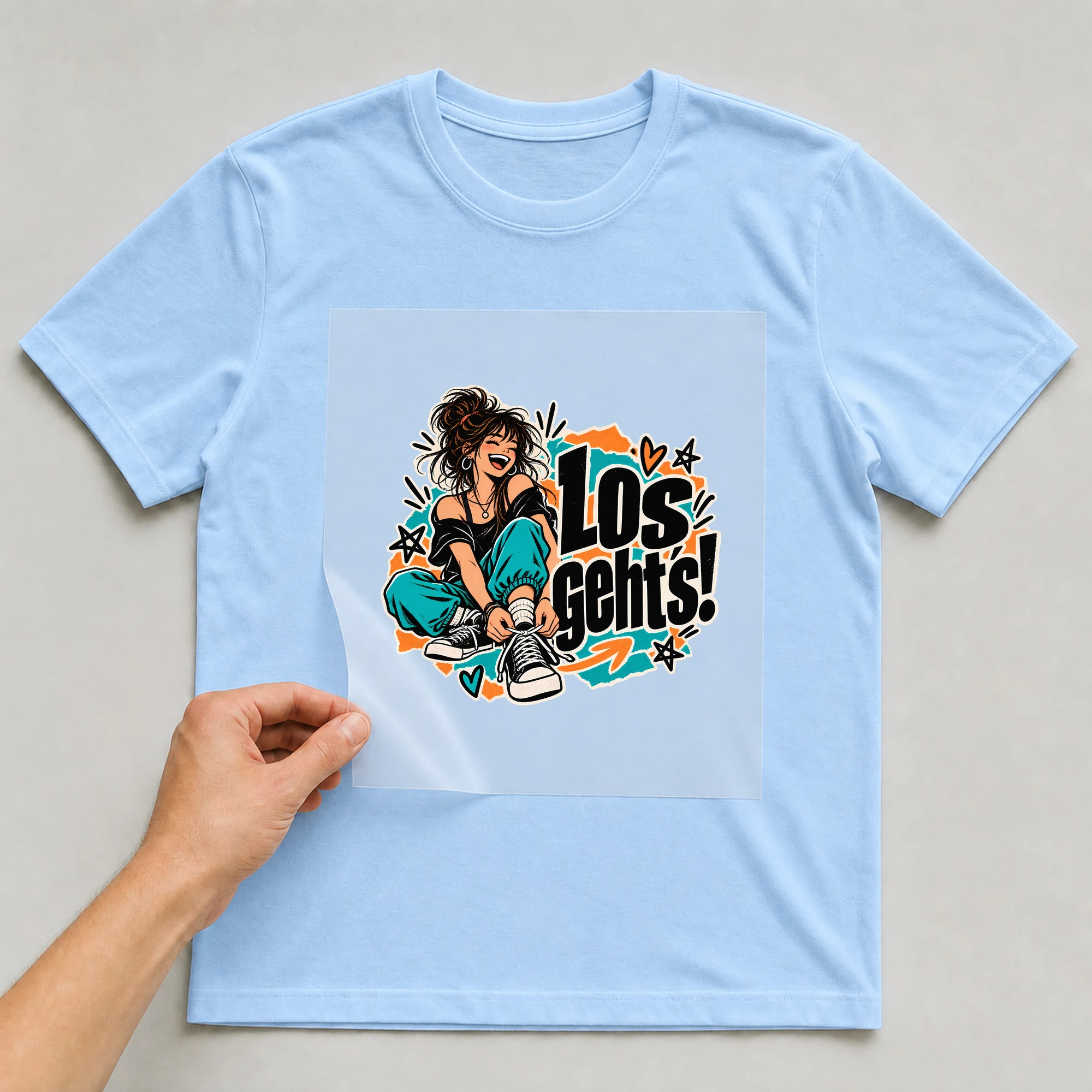 Bügelbild „Los geht's!“ auf babyblauem T-Shirt, Folie wird aufgelegt